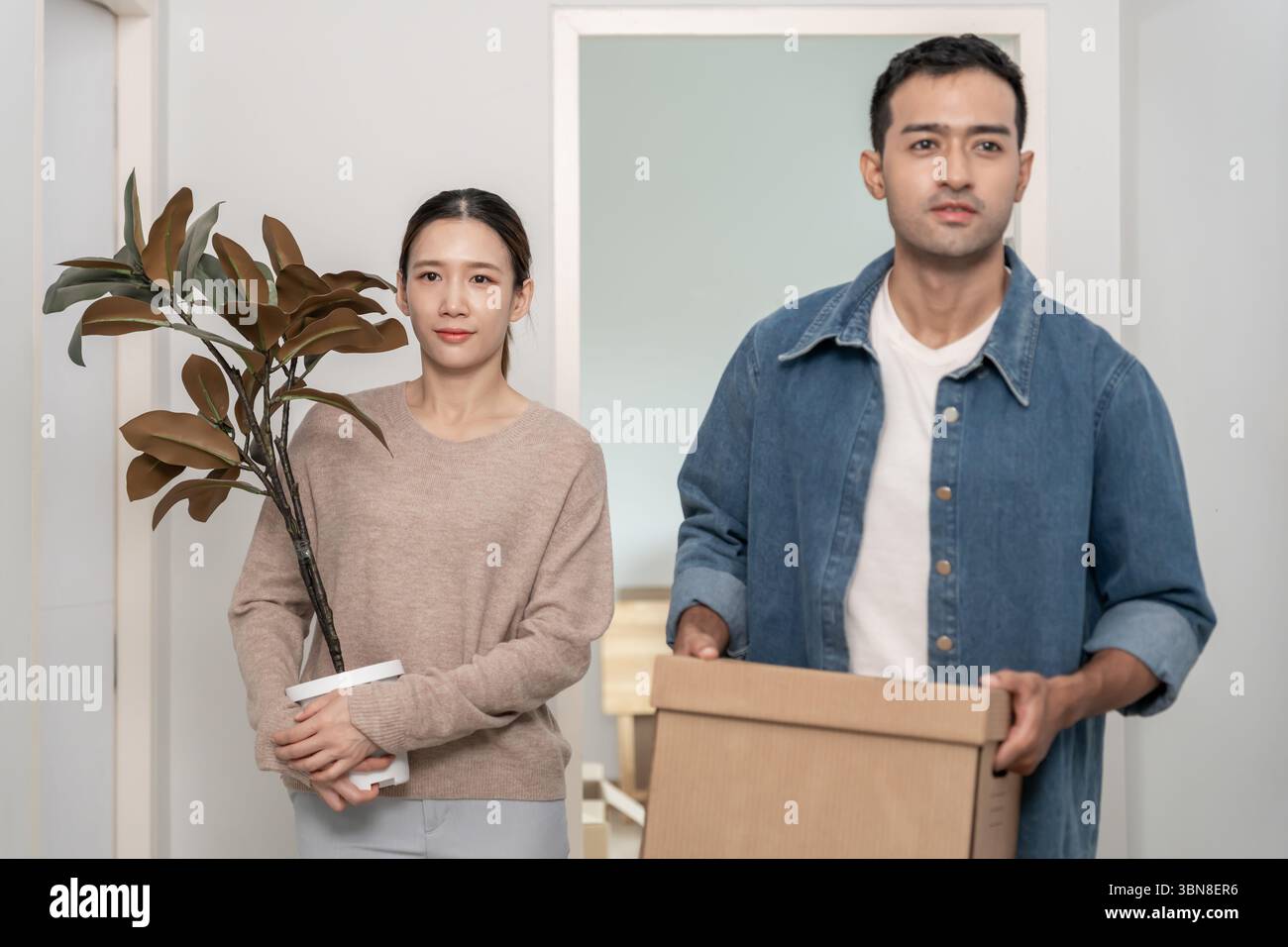 Umzugshaus, Ehemann und Ehefrau halten Box und Möbel für eine neue Wohnung oder ein neues Zuhause, im Zimmer war eine Pappschachtel mit persönlichen Sachen und Stockfoto