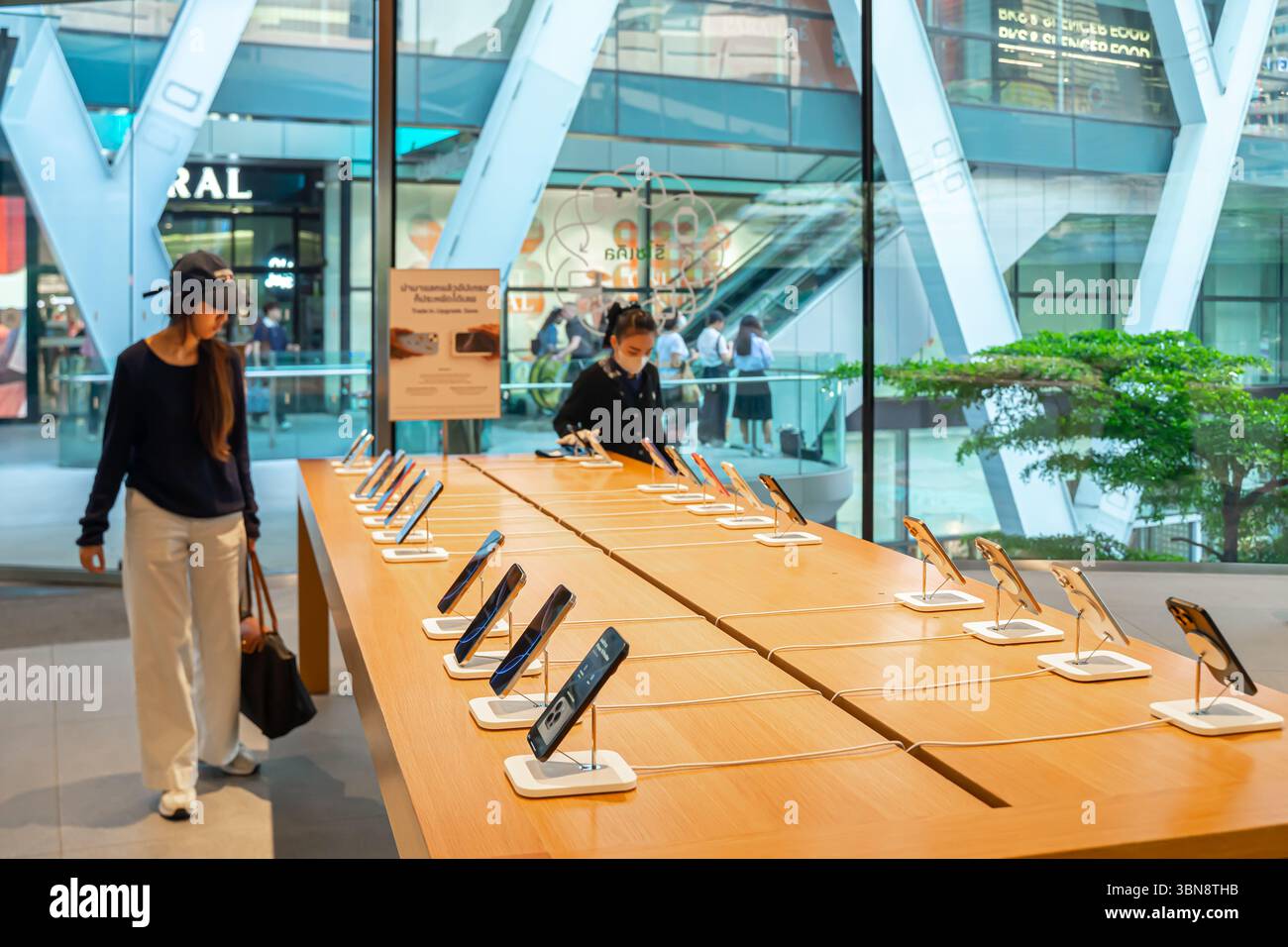 Eine Kundin, die neue iPhones im Display durchsucht, Apple Central World, Bangkok, Thailand Stockfoto