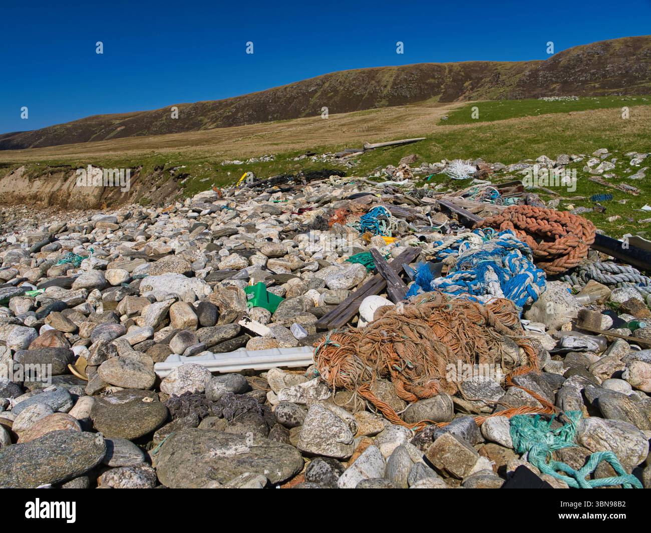 Plastikmüll und Seile an einem felsigen Strand in Newgord, Unst, Shetland, heben Umweltbedenken hervor. Stockfoto