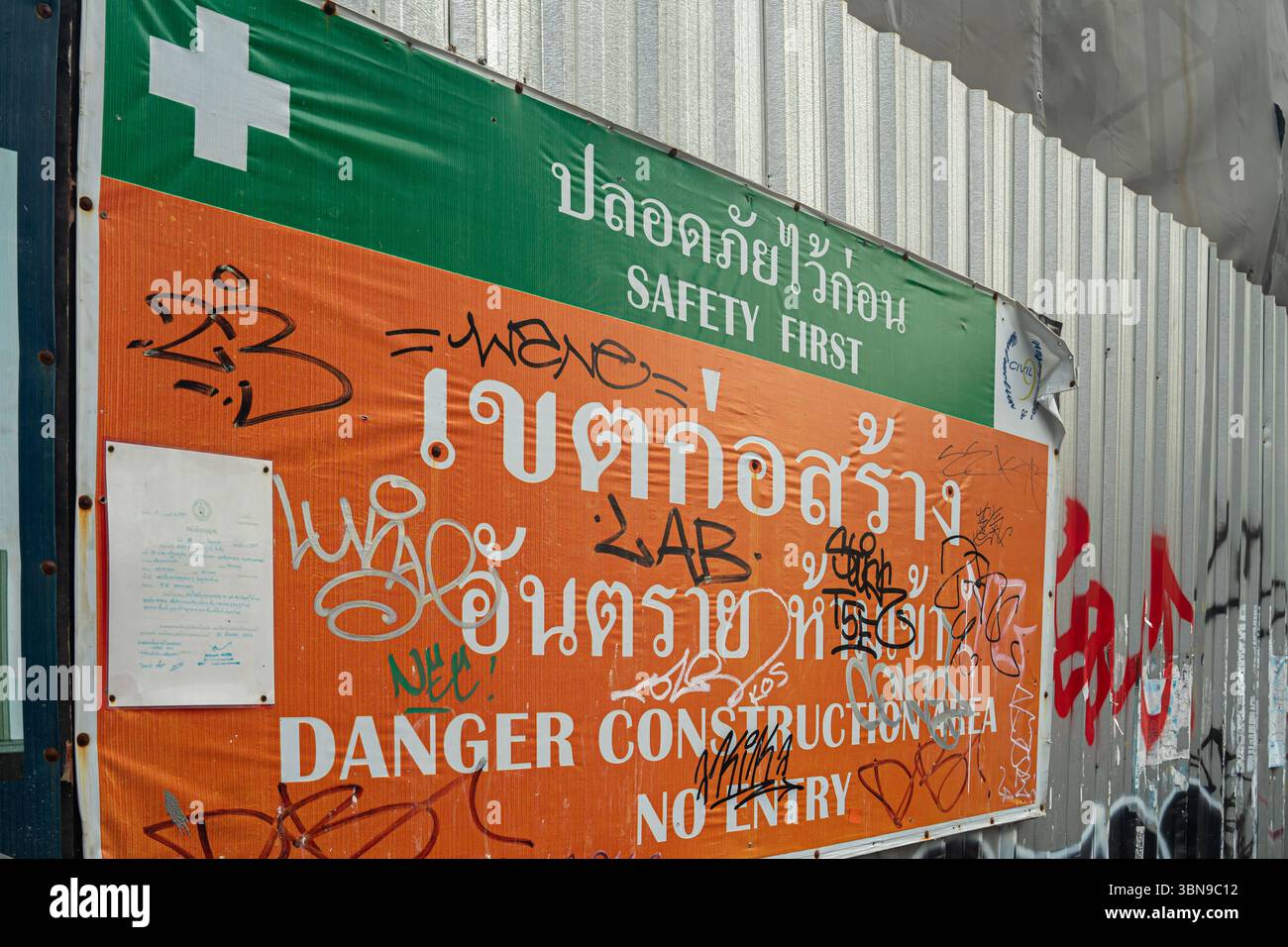 Sicherheitsschild und Baustellenschild auf Thai und Englisch sind mit Graffiti bedeckt. Bangkok, Thailand Stockfoto