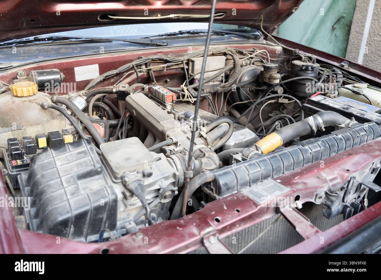 Nahaufnahme eines alten Nissan-Fahrzeugs mit geöffneter Motorhaube mit Motorkomponenten. Das Konzept der Fahrzeugwartung, -Reparatur und Oldtimer. Stockfoto
