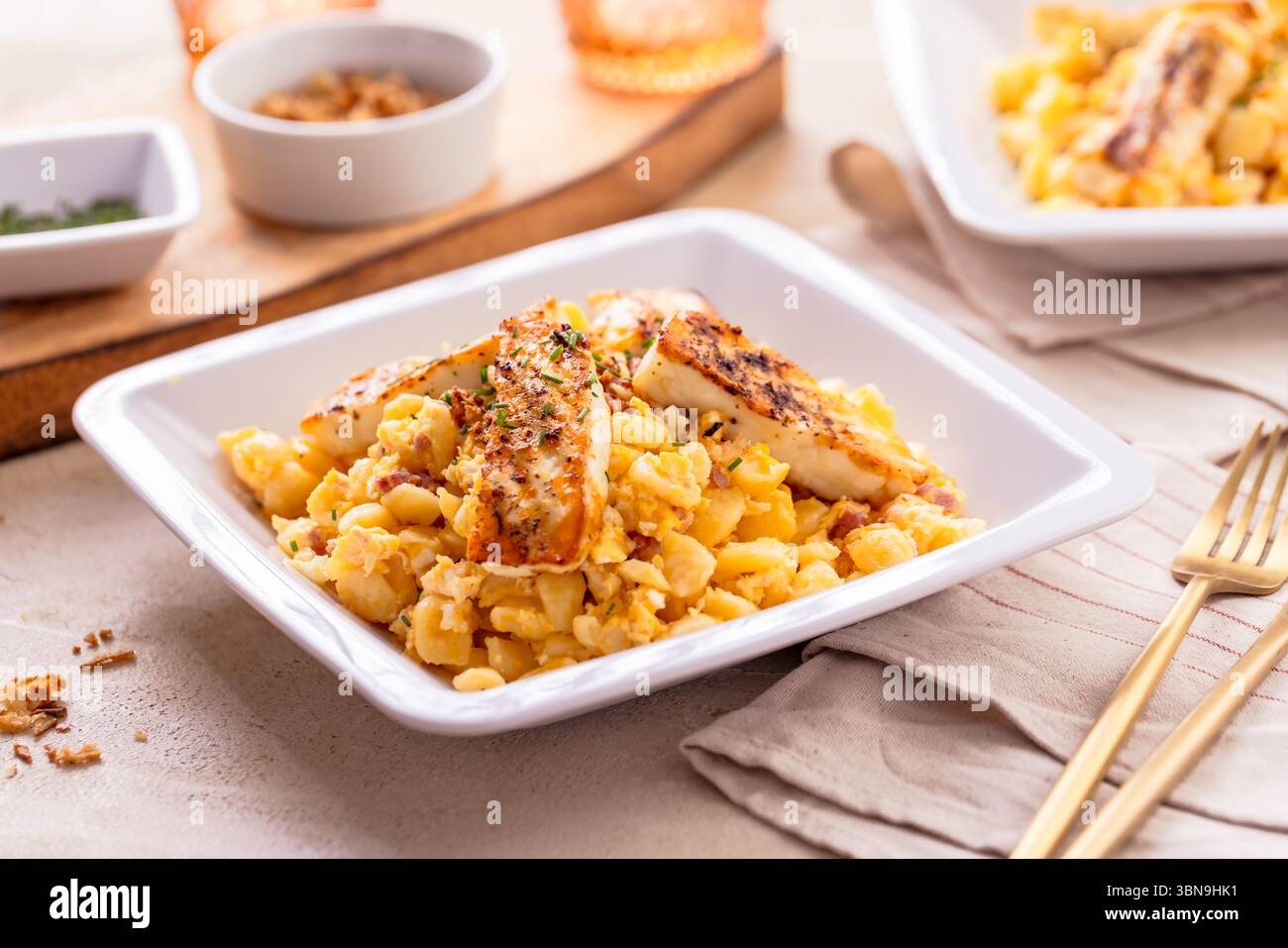 Deutsche Eierknödel mit Speck, gebratenen Zwiebeln und gegrilltem Halloumi-Käse Stockfoto