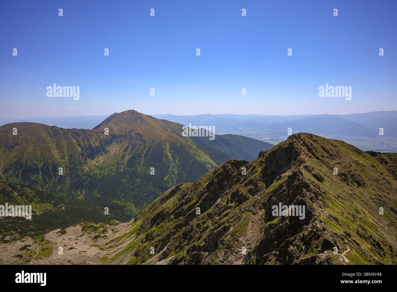 Atemberaubendes Panorama auf Berggipfel und Täler unter klarem blauen Himmel, mit atemberaubender Aussicht für Wanderer. Stockfoto
