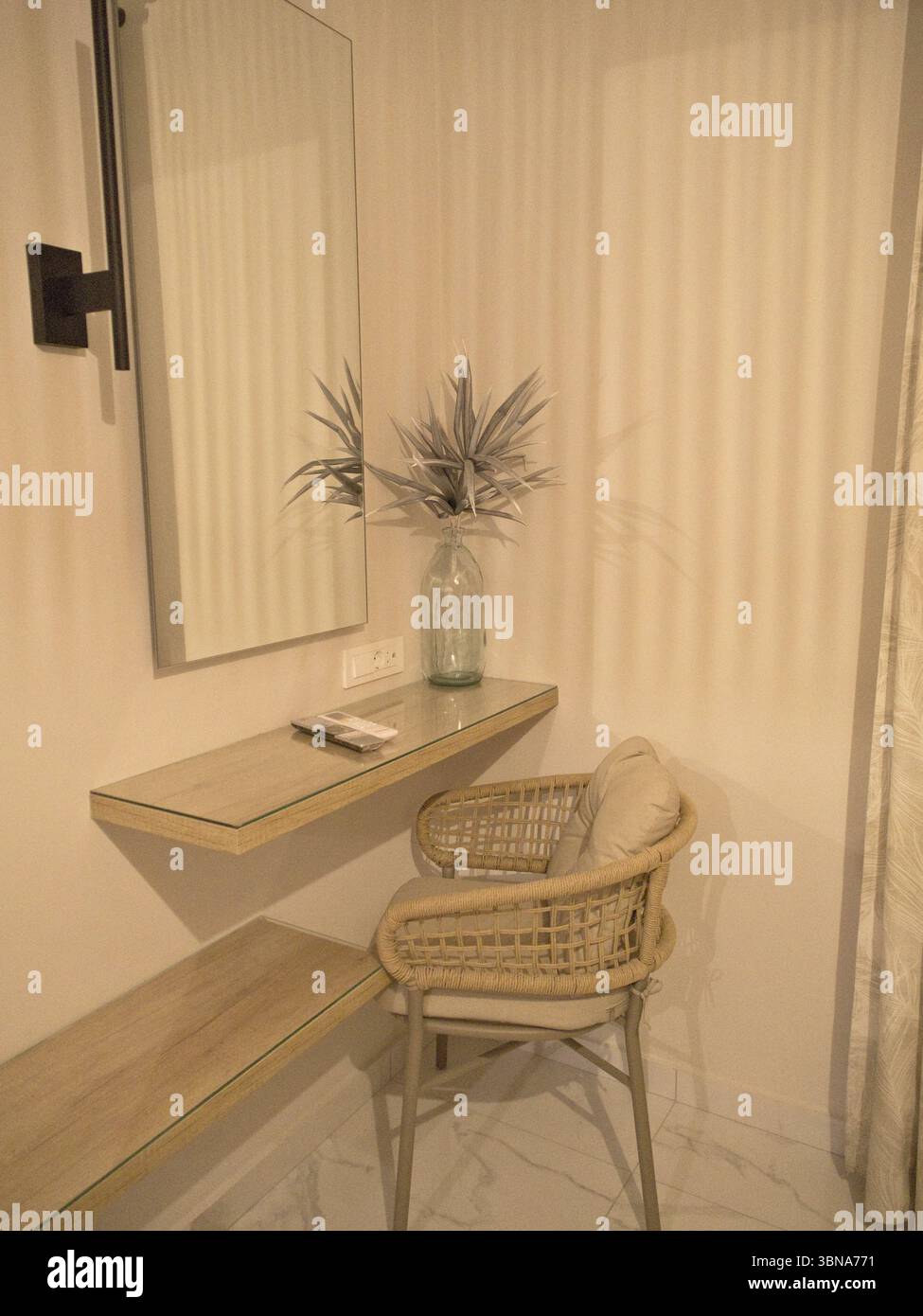 Gemütlicher und minimalistischer Sitzbereich in neutralen Farben mit ästhetischem Stuhl, Spiegel und Regal in ruhiger Inneneinrichtung. Stockfoto