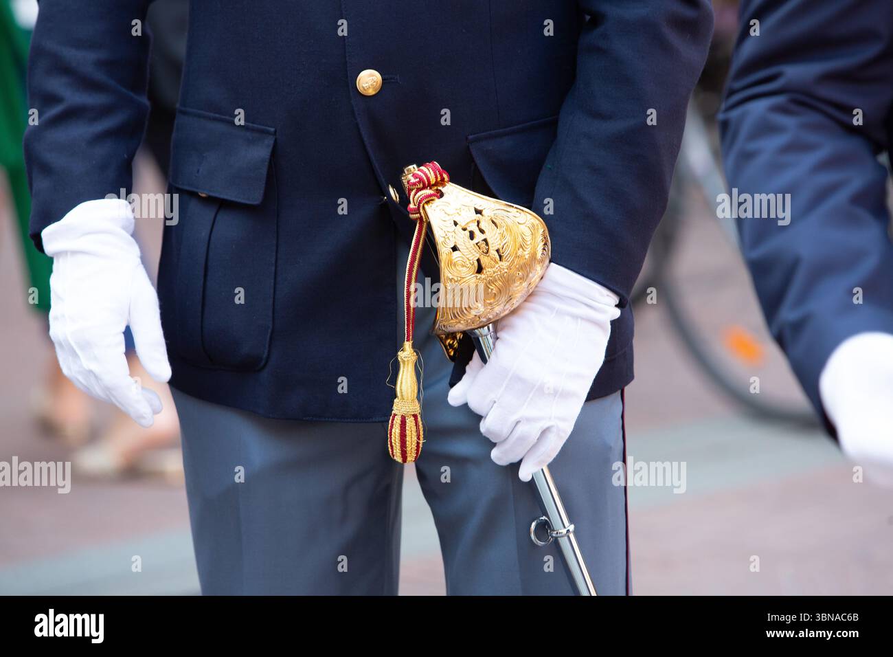 Nahaufnahme eines Offiziers mit weißen Handschuhen, der ein zeremonielles Schwert mit einem eleganten goldenen Griff hält Stockfoto