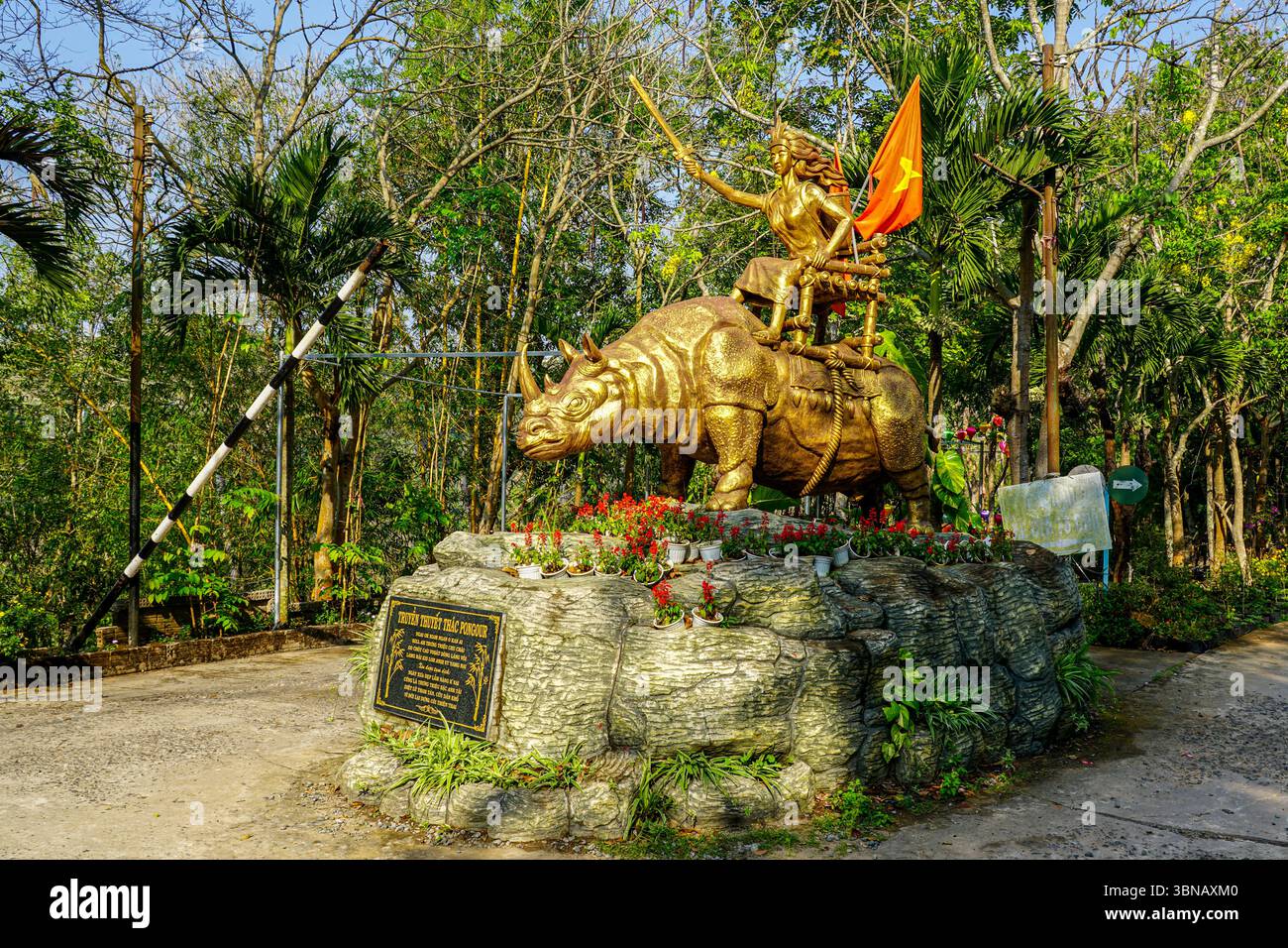 Dalat, Vietnam - 24. März 2025: Diese goldene Statue symbolisiert die legendäre Heldin des Pongour-Wasserfalls, die auf einem Nashorn mit Schwert und Flagge reitet Stockfoto