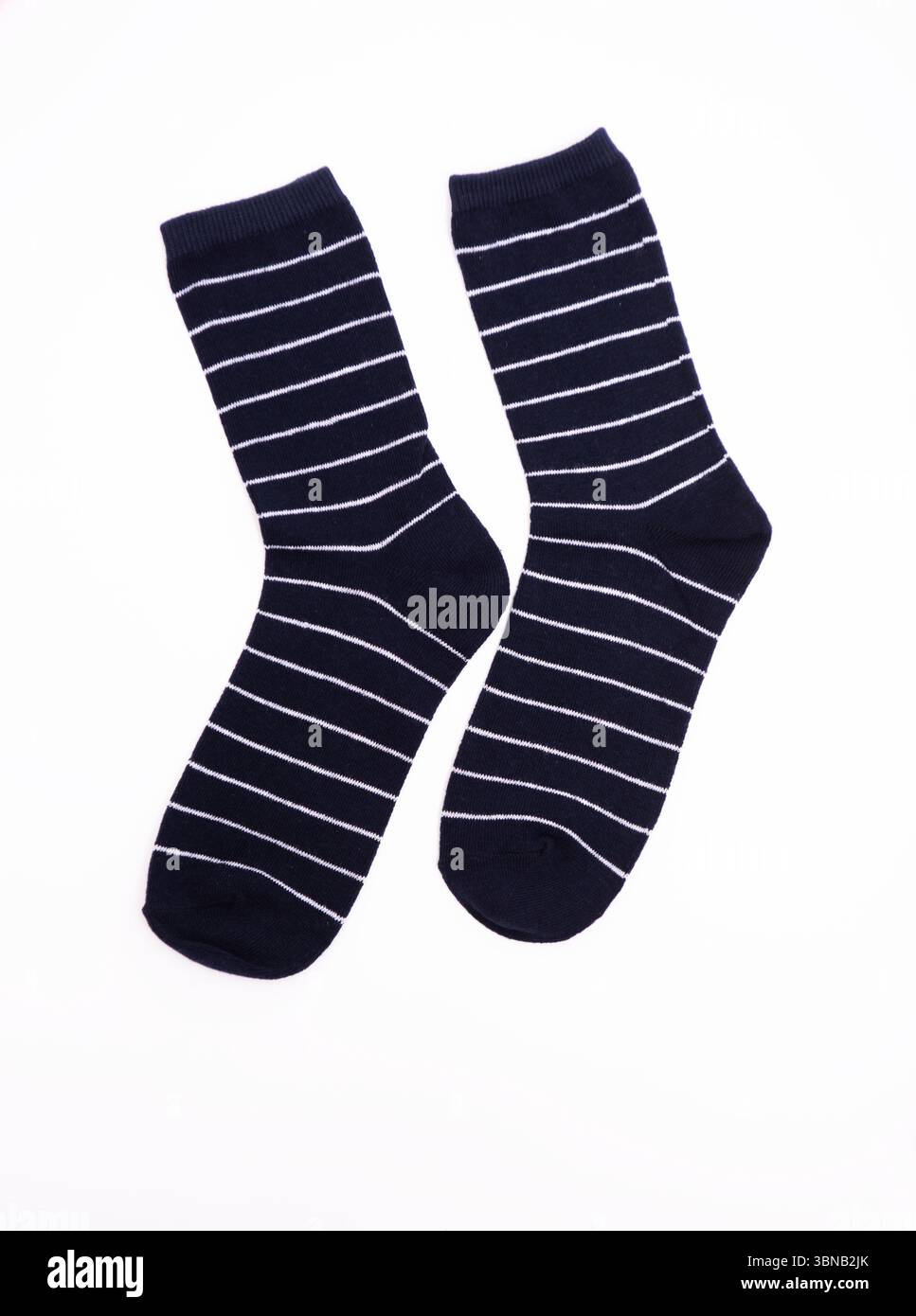 Marineblaue Socken mit weißen Streifen sind auf einem makellosen weißen Hintergrund präsentiert und heben die Stoffstruktur und das stilvolle Design für Mode hervor Stockfoto