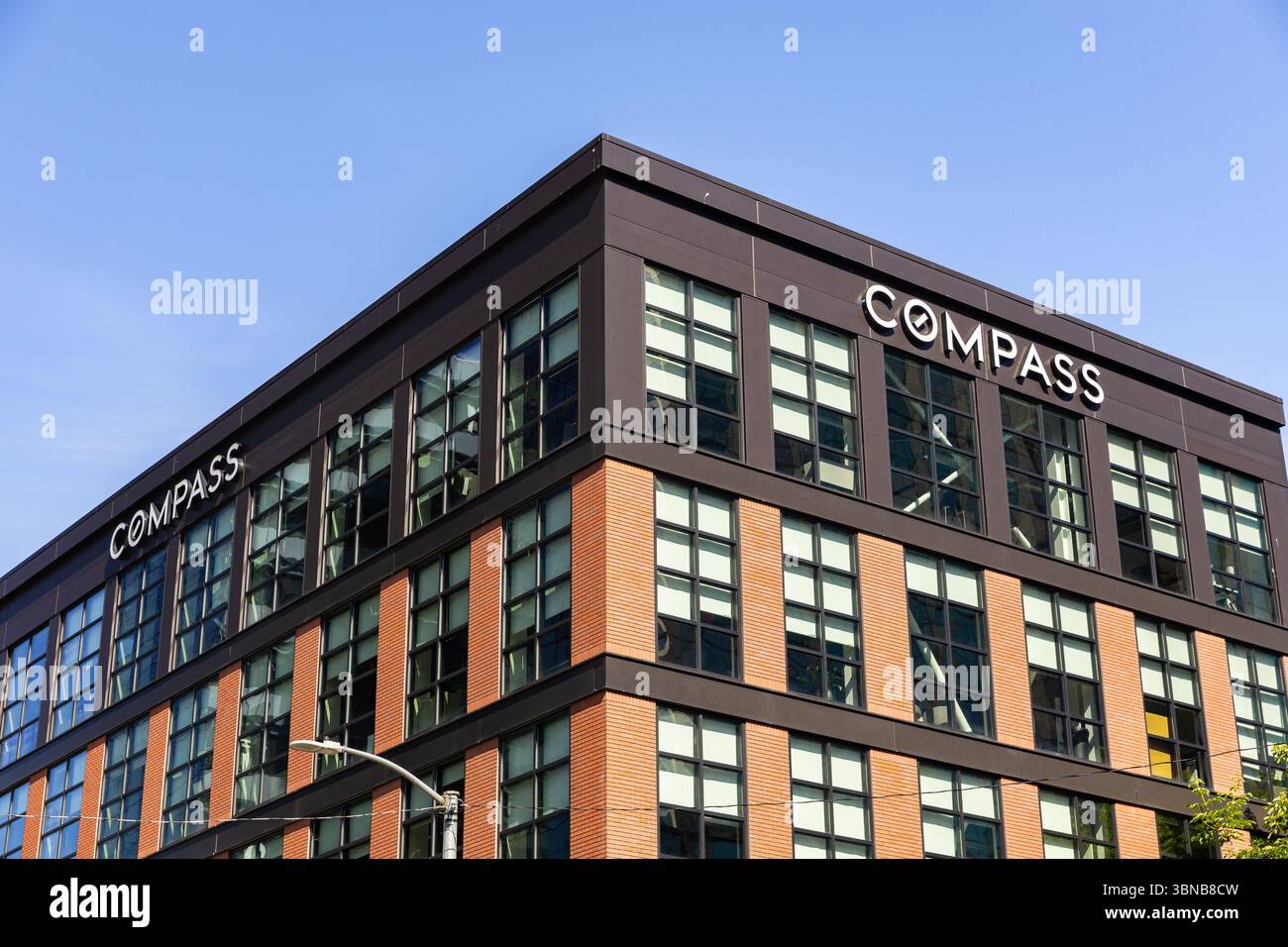 Das Compass Real Estate Logo auf einem Backsteingebäude in der Innenstadt von Seattle, WA. Stockfoto