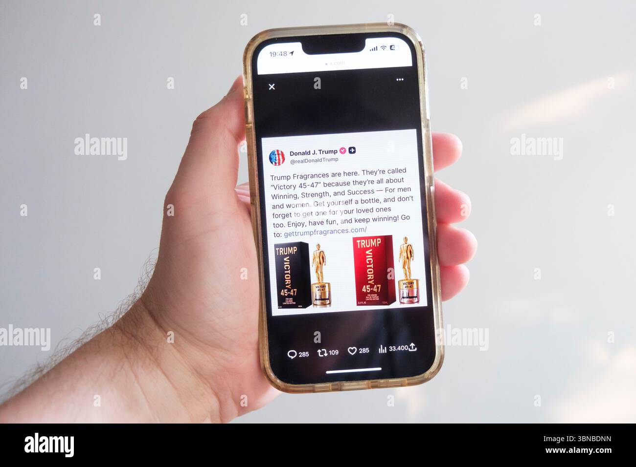 Ein Nutzer sieht einen Social-Media-Beitrag von Donald Trump auf X, früher Twitter, auf seinem Smartphone, in dem der US-Präsident sein Parfüm Victory 45-47 präsentiert Stockfoto