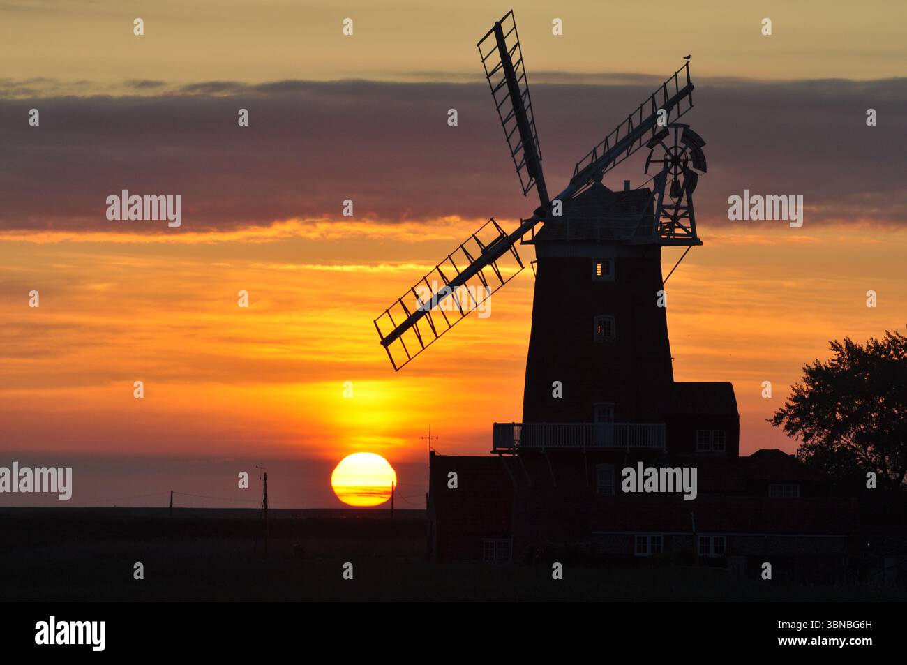 Sonnenaufgang hinter der Mühle in Cley-next-the-Sea Norfolk England. Stockfoto