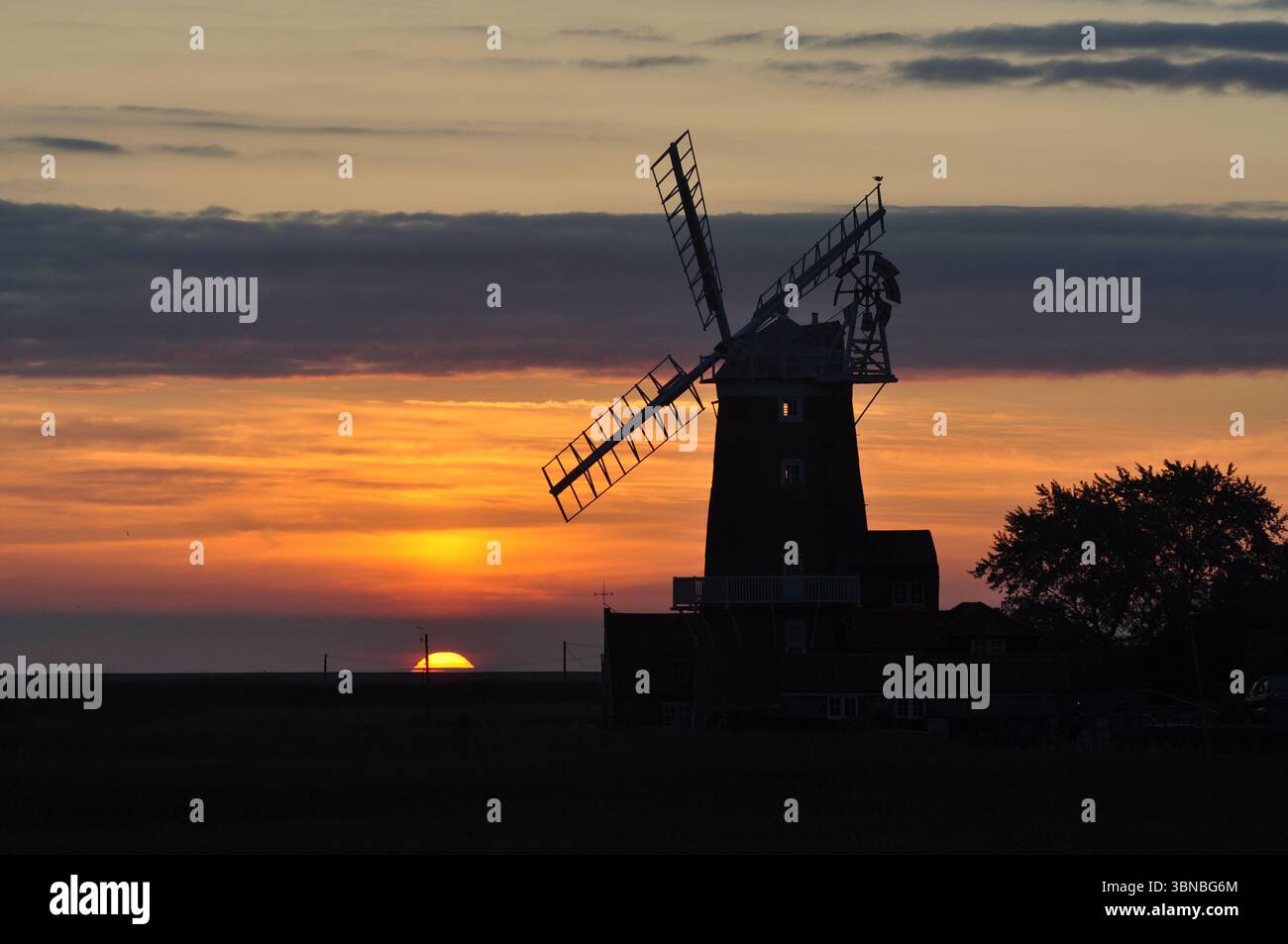 Sonnenaufgang hinter der Mühle in Cley-next-the-Sea Norfolk England. Stockfoto