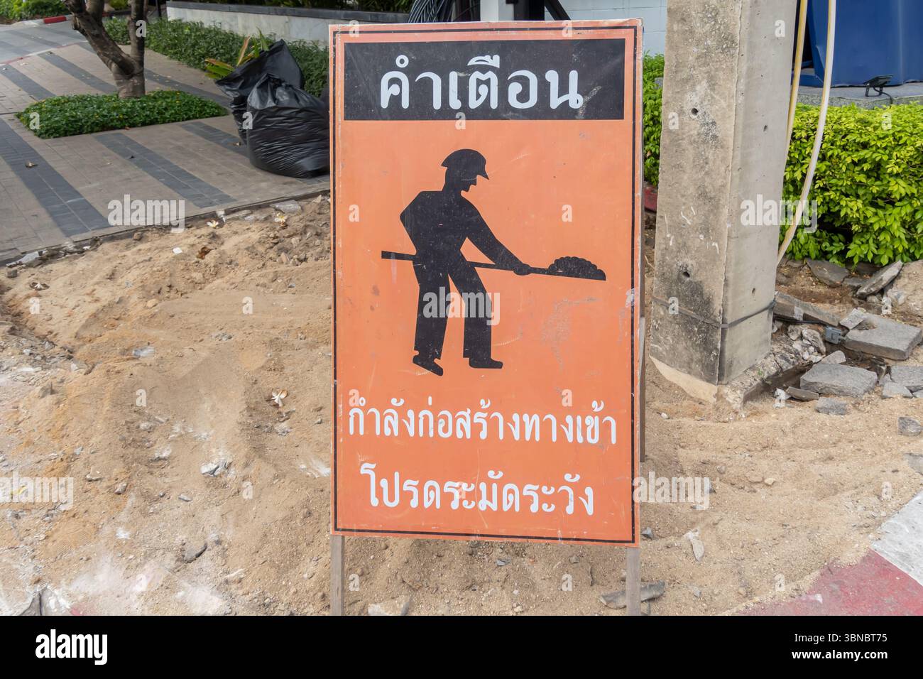 Ein Schild auf Thai warnt vor Bauarbeiten auf dem Weg. Hua Hin, Thailand Stockfoto