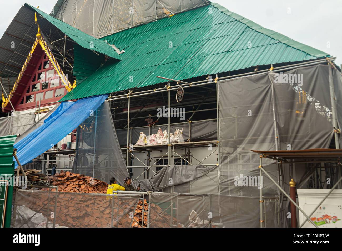 Ein historisches thailändisches Gebäude im Bau, Teil des Königspalastkomplexes, das mit Gerüsten und Schutzplanen bedeckt ist. Bangkok, Thailand Stockfoto