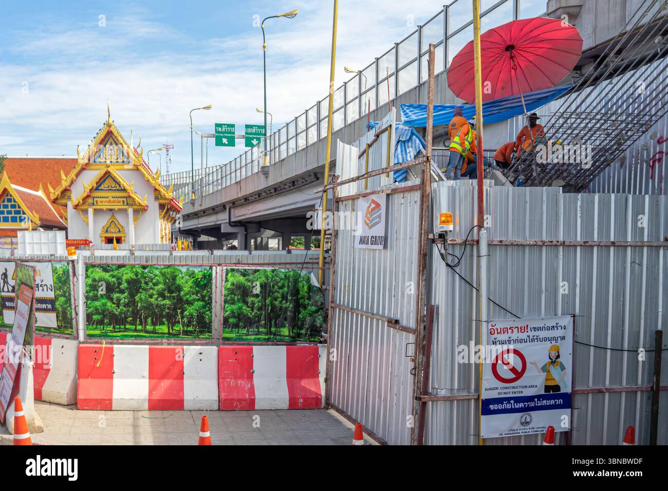 Arbeiter unter Schirm, Baustelle mit Barrieren neben einem traditionellen thailändischen Gebäude, unter der Autobahn, Bangkok Noi, Thailand Stockfoto