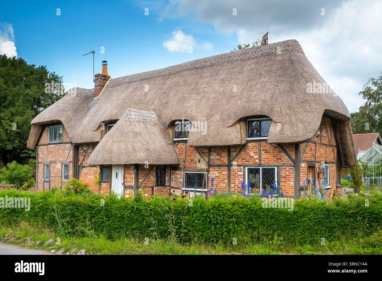 Malerisches traditionelles Backsteingebäude im ÔTudorÕ-Stil mit Strohdach und bleihaltigen Lichtfenstern in Hampshire, England, Großbritannien Stockfoto