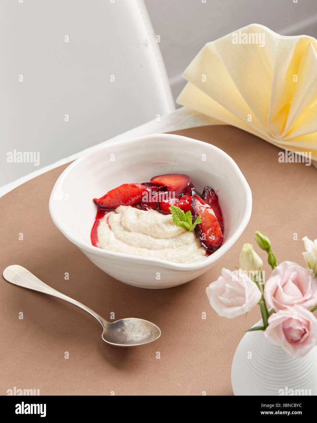 Cremiger veganer Grießpudding mit Fruchtsauce – ein warmes, wohltuendes Dessert mit festlicher Serviette als Teil eines pflanzlichen Menüs. Stockfoto