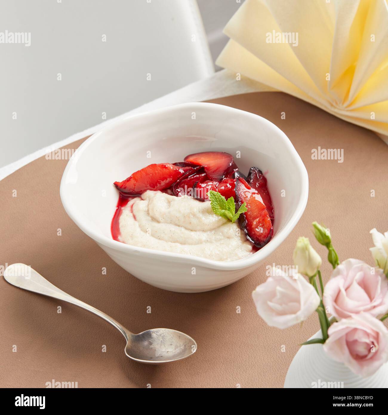 Cremiger veganer Grießpudding mit Fruchtsauce – ein warmes, wohltuendes Dessert mit festlicher Serviette als Teil eines pflanzlichen Menüs. Stockfoto