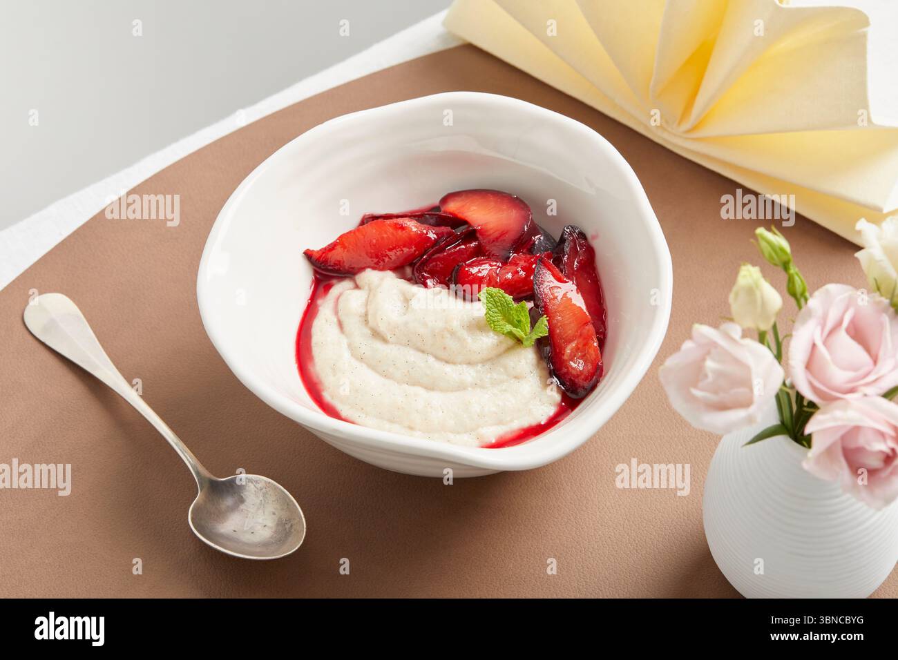 Cremiger veganer Grießpudding mit Fruchtsauce – ein warmes, wohltuendes Dessert mit festlicher Serviette als Teil eines pflanzlichen Menüs. Stockfoto