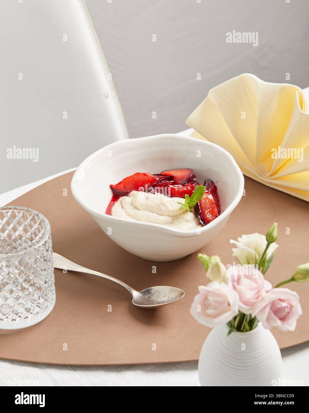 Cremiger veganer Grießpudding mit Fruchtsauce – ein warmes, wohltuendes Dessert mit festlicher Serviette als Teil eines pflanzlichen Menüs. Stockfoto