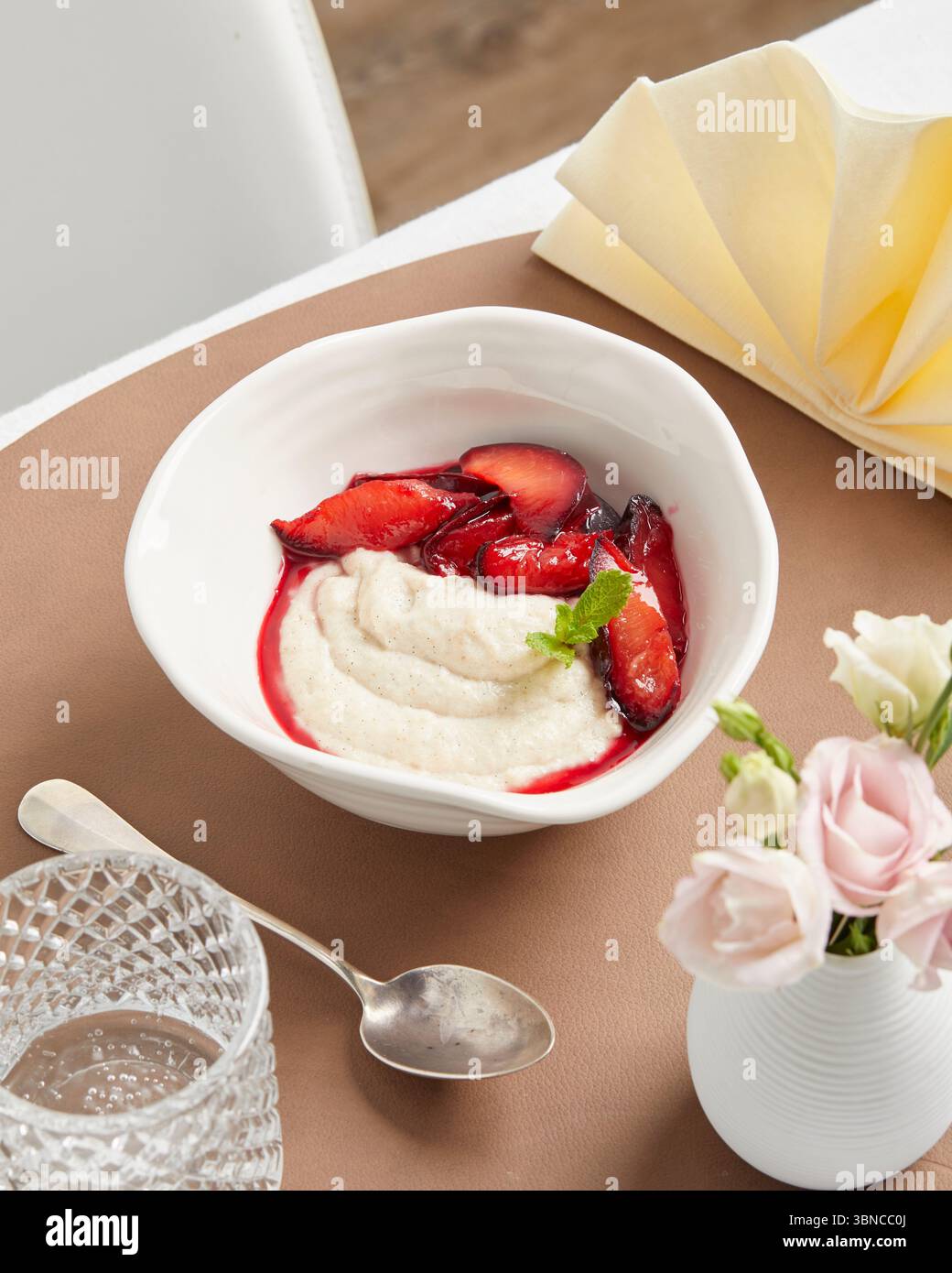 Cremiger veganer Grießpudding mit Fruchtsauce – ein warmes, wohltuendes Dessert mit festlicher Serviette als Teil eines pflanzlichen Menüs. Stockfoto