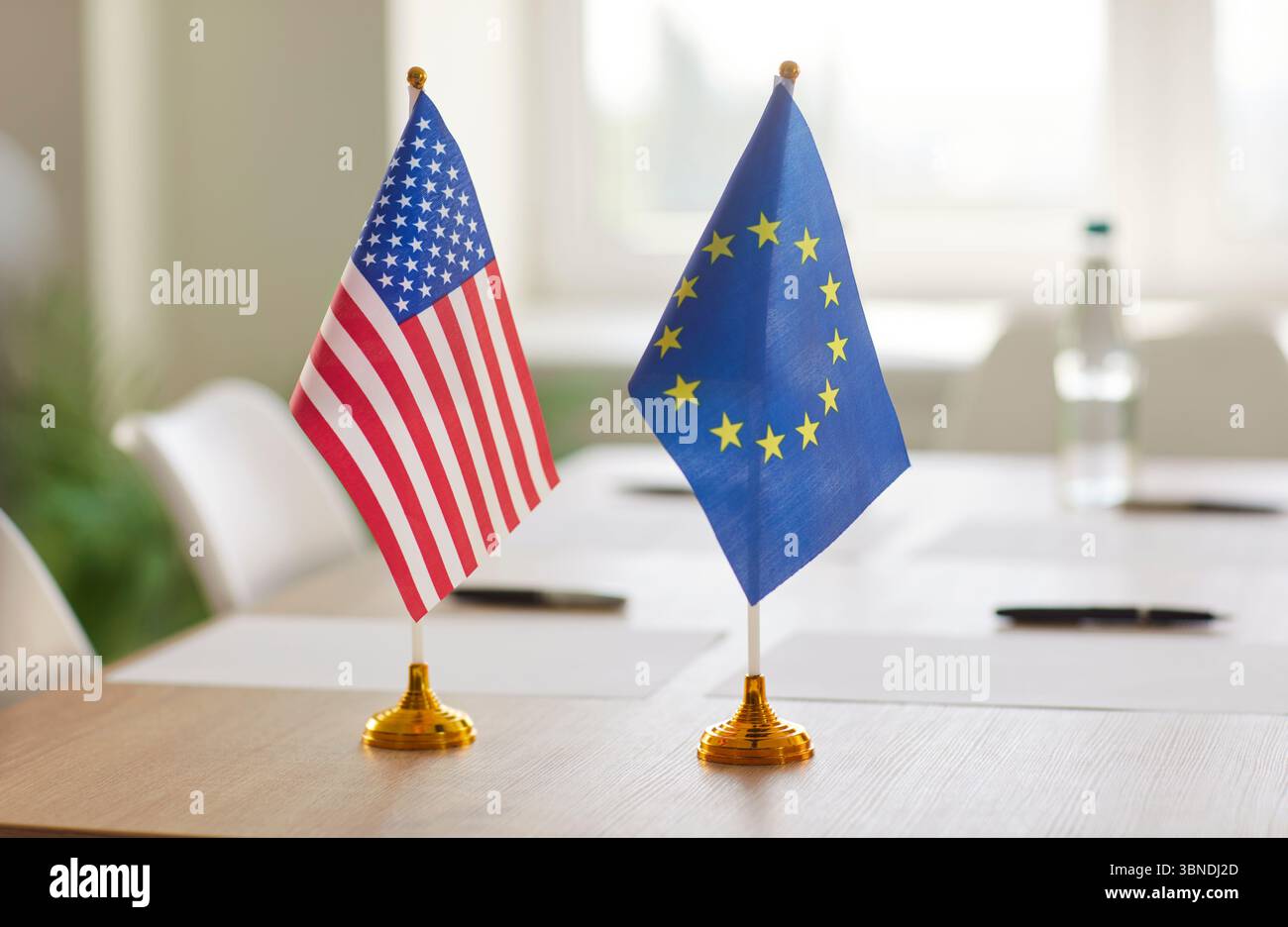 Flaggen der Vereinigten Staaten und der Europäischen Union auf dem Tisch, vorbereitet für diplomatische Verhandlungen oder Gipfeltreffen. Stockfoto