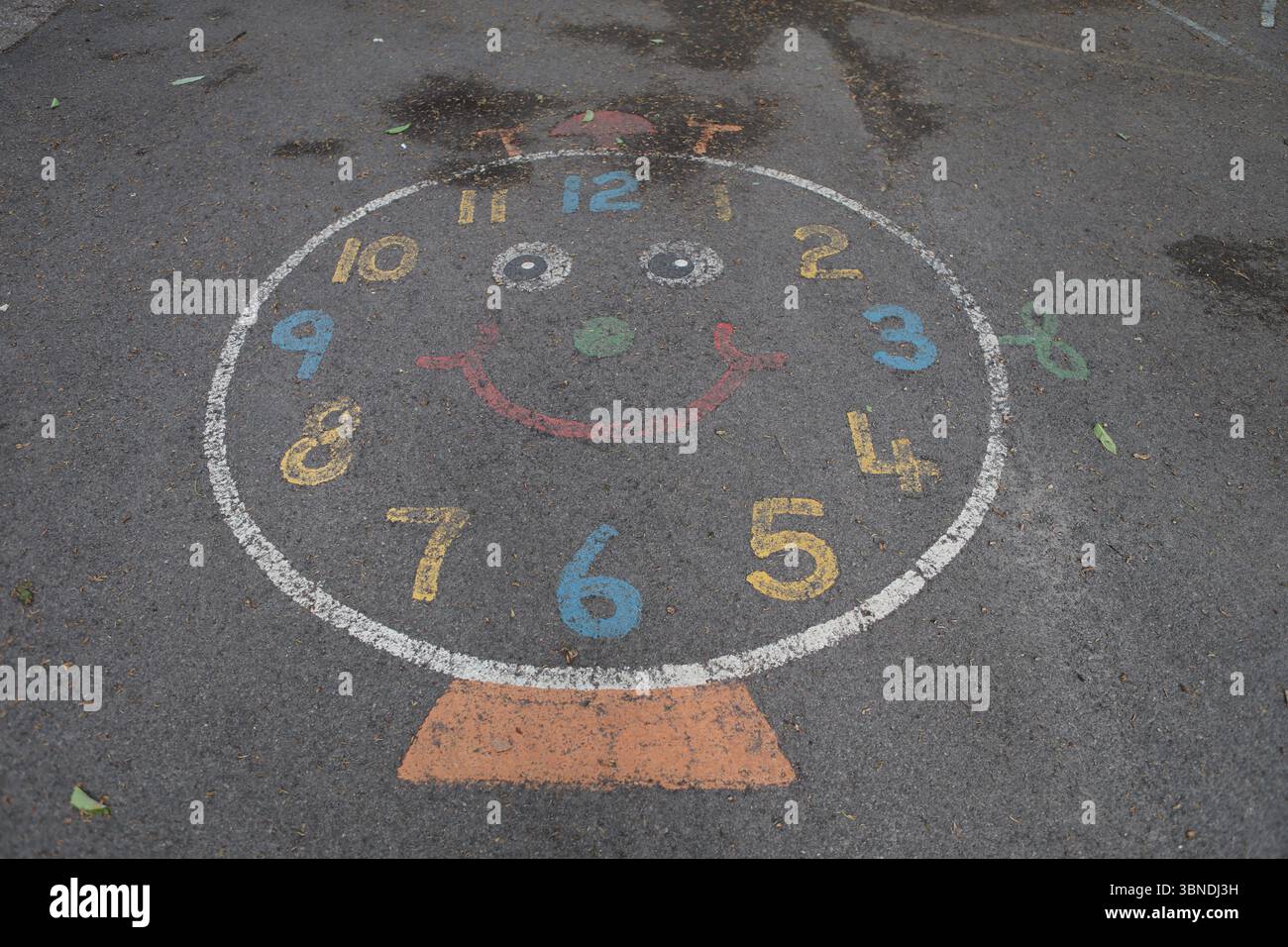 Auf Rollfeld gemalt auf der Uhr des Kinderspielplatzes, die die Zeit angibt, die die Zeit zu erzählen lernt Stockfoto
