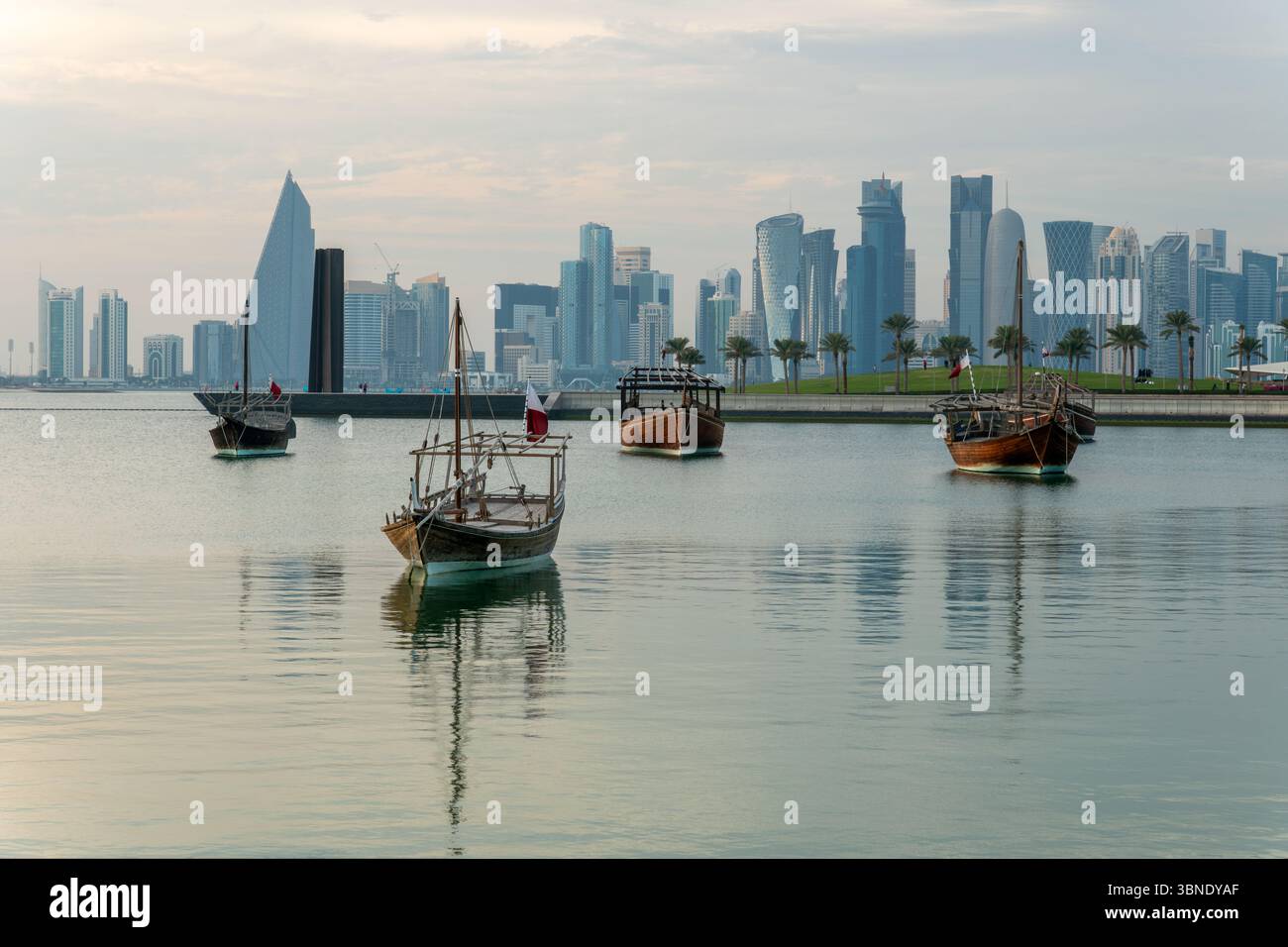 Traditionelle arabische Dhow-Boote im Hafen von Doha, Katar. Wunderschöne Meereslandschaft mit dem Meer und modernen Wolkenkratzern im Hintergrund. Stockfoto