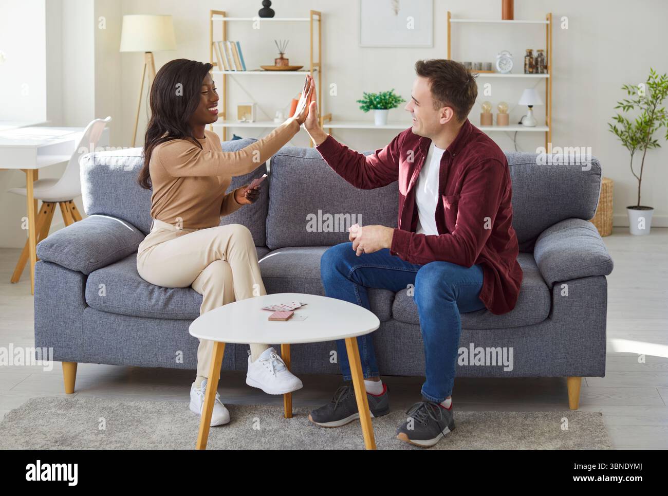 Multirassisches junges Paar, junge interrassische Familie zu Hause, die Kartenspiel spielt Stockfoto