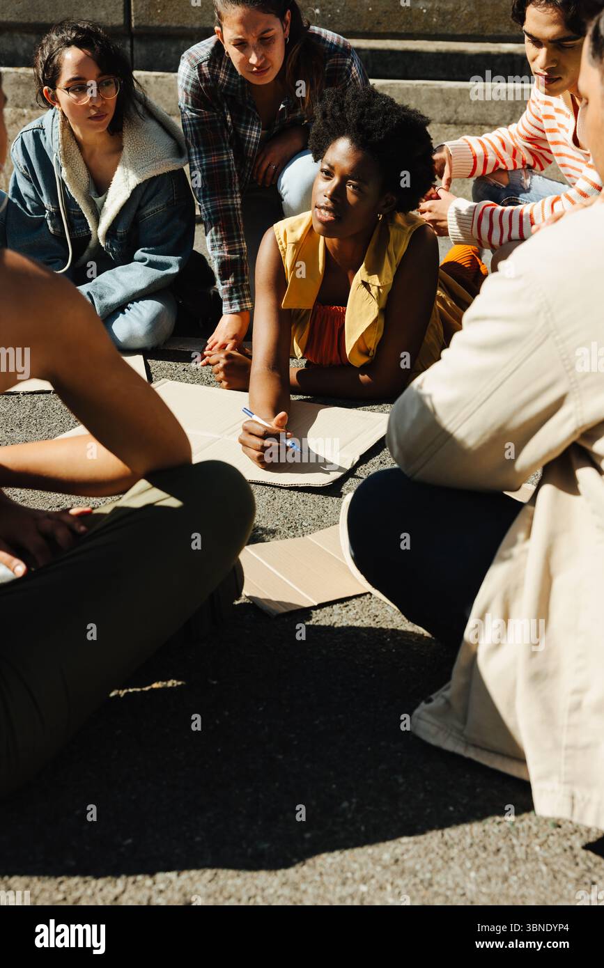 Eine Sammlung junger Menschen, die an einer Außendiskussion teilnahmen, die im Rahmen einer Initiative für sozialen Aktivismus mitwirkte. Die Gruppe scheint fokussiert zu sein, Emph Stockfoto