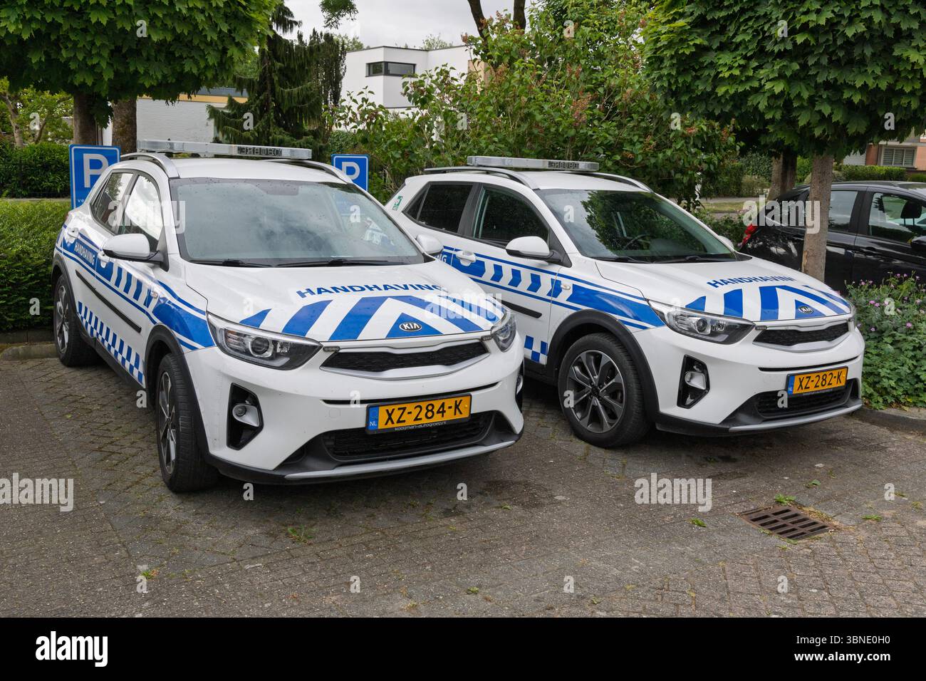 Zwei weiße und blaue „Handhaving“-Fahrzeuge (Vollstreckungsfahrzeuge), die im Freien geparkt sind und für öffentliche Sicherheit, kommunale Dienste und städtische Ordnung stehen. Amsterdam, N Stockfoto