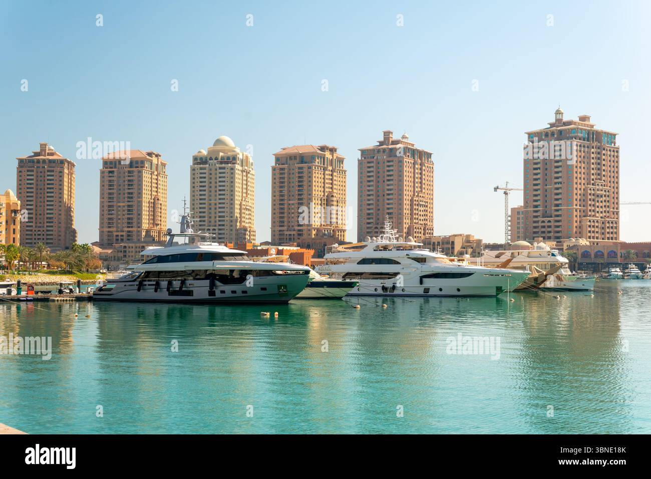 Doha, Katar - Arabische Marina im Peral Doha, Katar Sonnenuntergangsaufnahme, bei der Boote und Yachten im arabischen Golf und Wohngebäude im Hintergrund angedockt werden Stockfoto