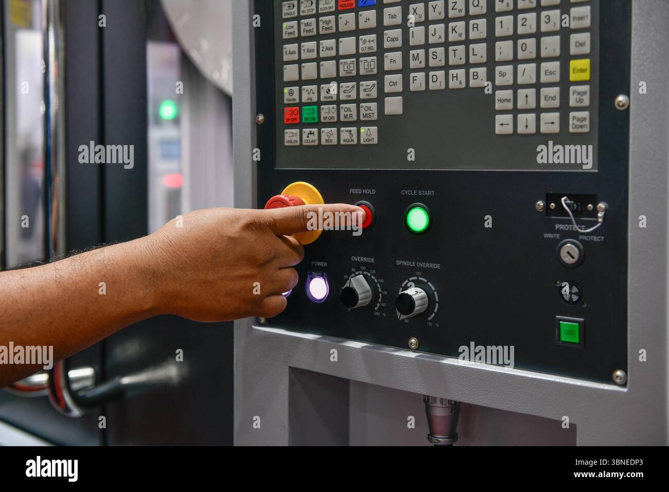 Die Bedienerhand der Maschine schaltet das Bedienfeld der Industriemaschine ein. Taster des Technikers auf dem Bedienfeld Stockfoto