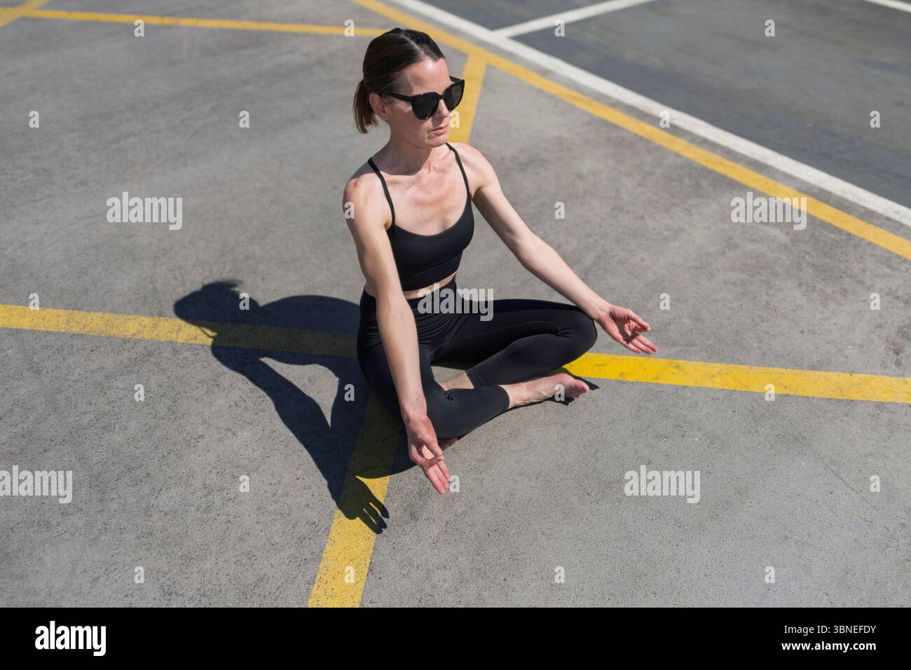 Frau übt Outdoor Yoga in entspannter Pose unter hellem Sonnenlicht Stockfoto