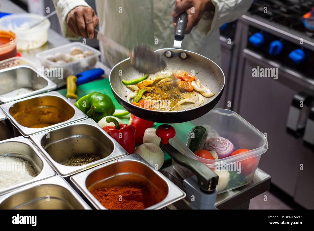 Sheffield UK: 25. Juni 2019 - Ein Koch wählt die Gewürze für eine neue Sauce aus. Kochen in einer belebten indischen Restaurantküche, Worksop Spice Stockfoto