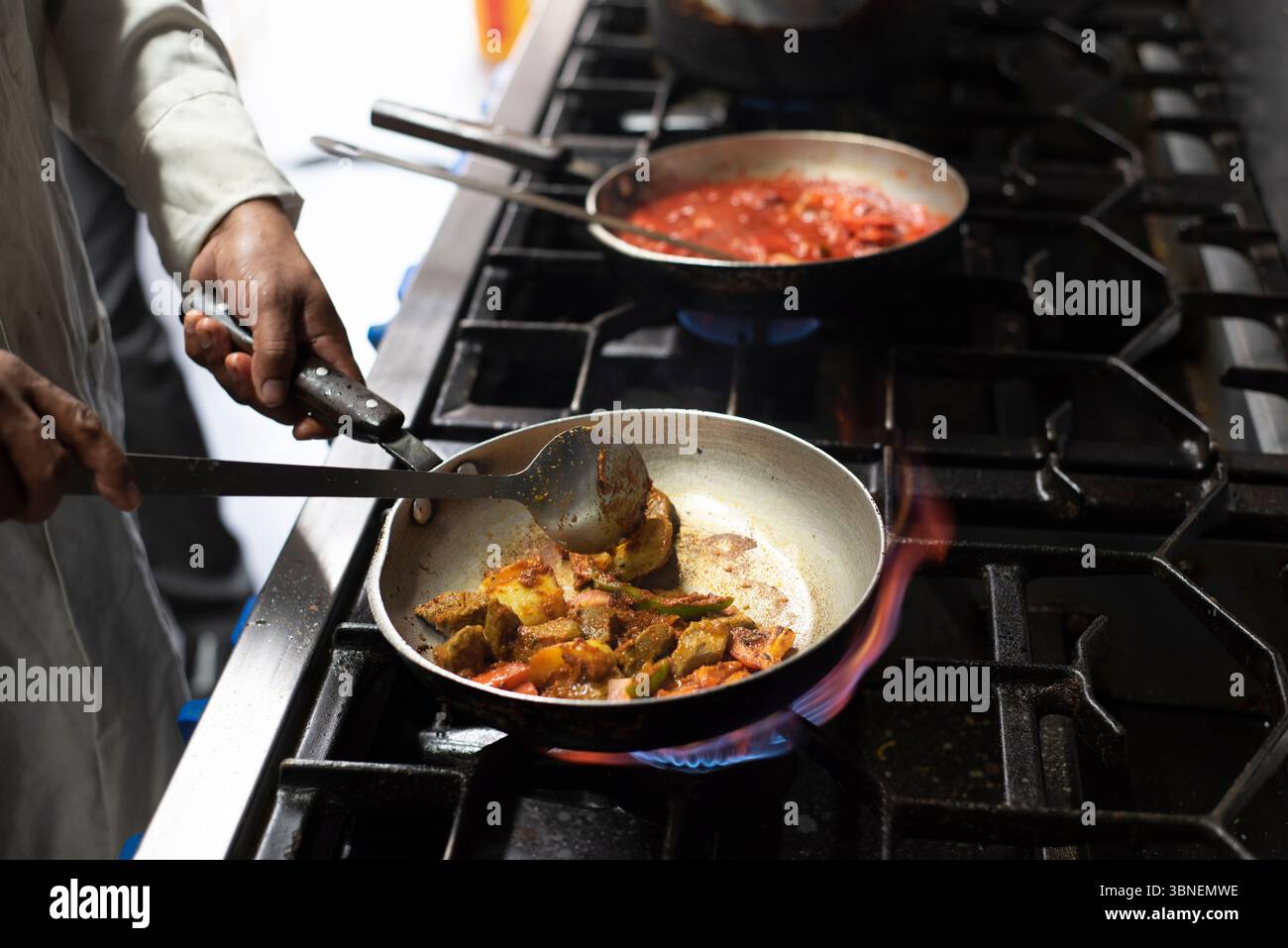 Sheffield UK: 25. Juni 2019 - Ein Koch rührt die Sauce um. Kochen in einer belebten indischen Restaurantküche, Worksop Spice Stockfoto