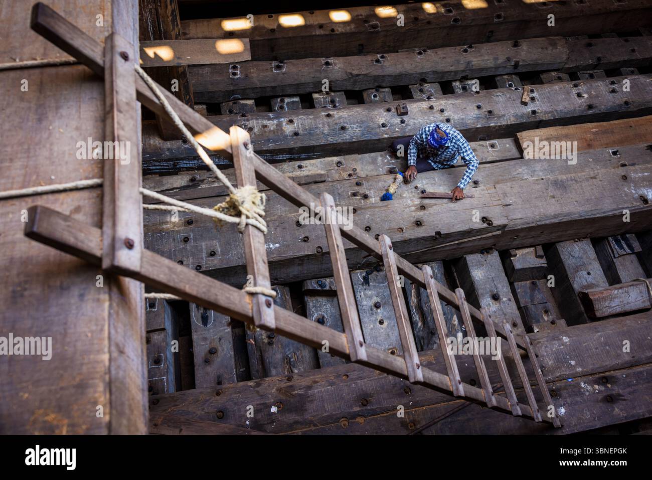 Ein Schiffbauer arbeitet an einem Holzboot im Bau, Mandvi, Gujarat, Indien Stockfoto