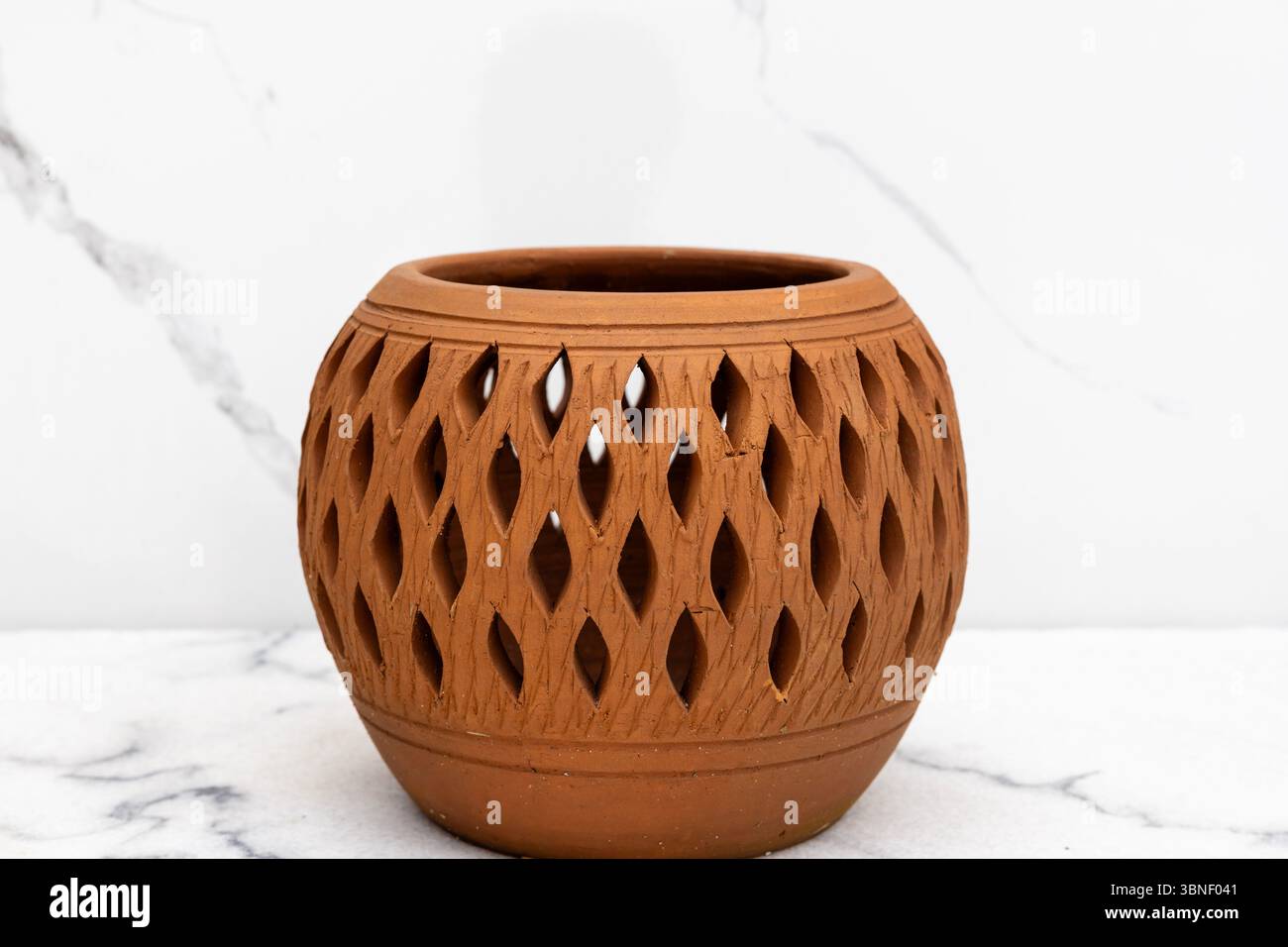 Handwerklich entworfener Tontopf mit symmetrischen Schnitzereien, ideal für Inneneinrichtung oder traditionelle Themen. Stockfoto