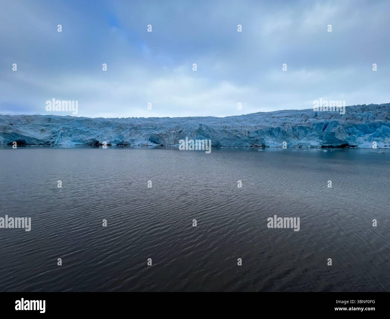 Gletscher Nordenskiöldbreen trifft unter einem dramatischen, bewölkten Himmel auf das Meer und schafft eine ruhige Landschaft. Spitzbergen, Svalbard Stockfoto