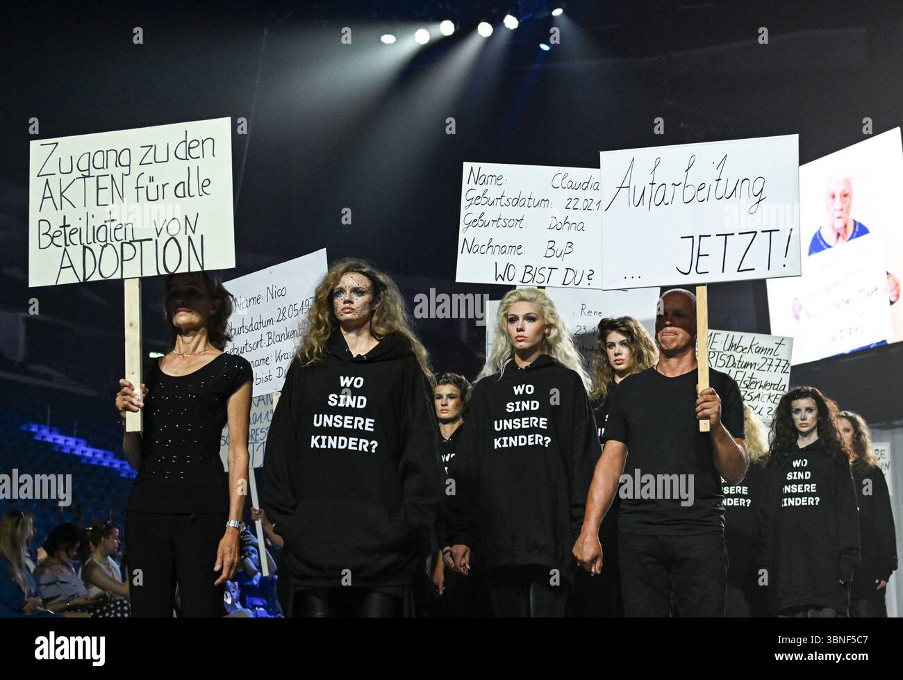 Berlin, Deutschland. Juli 2025. Als Teil der Show von Designer Kilian Kerner auf der Modeschau 'DDR. Die gestohlenen Kinder für Frühjahr/Sommer 2026 im Collevtivefour Space in der Uber Arena zeigen Models und Mitarbeiter Plakate zum Thema. Quelle: Jens Kalaene/dpa/Alamy Live News Stockfoto