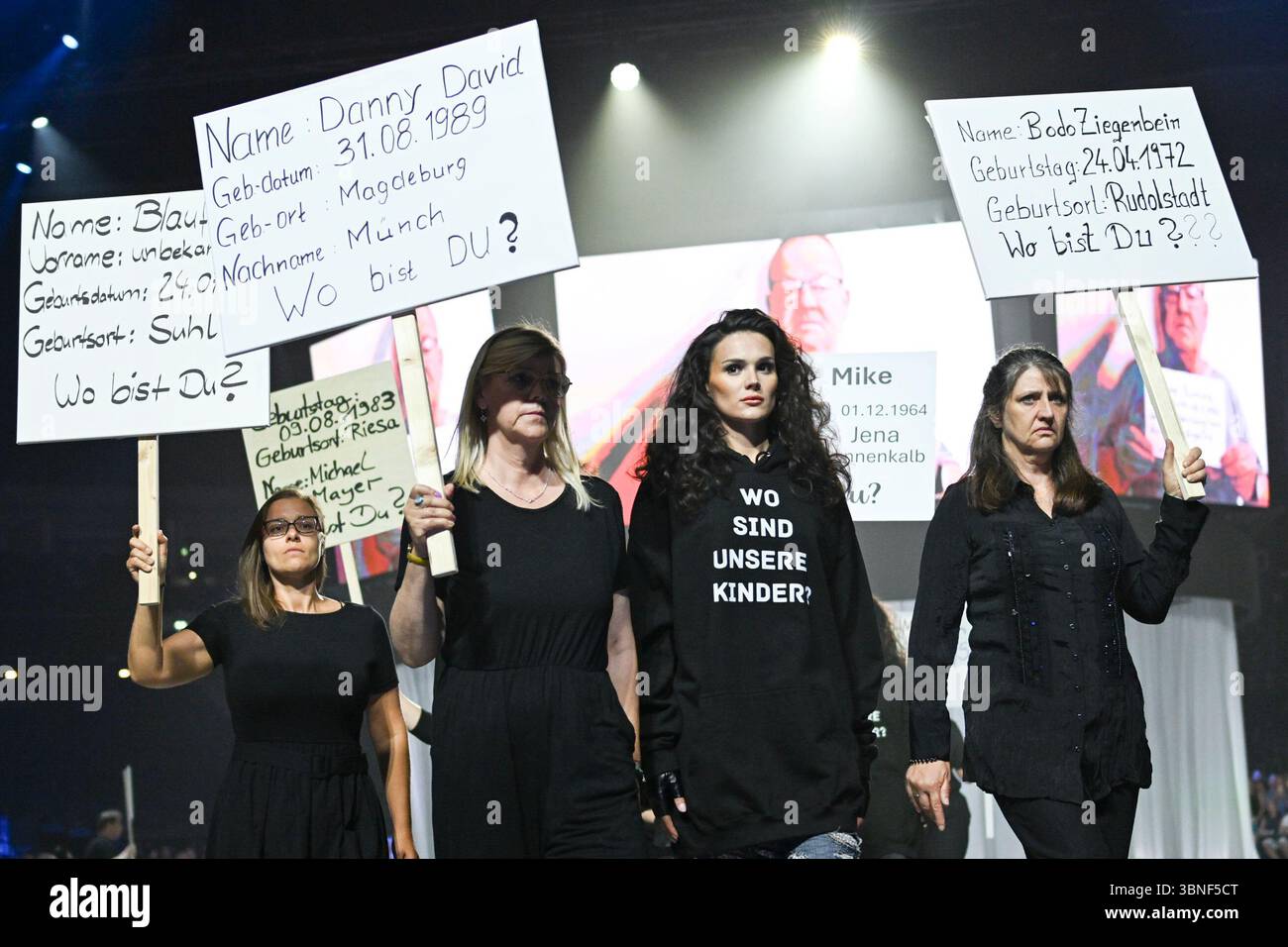 Berlin, Deutschland. Juli 2025. Als Teil der Show von Designer Kilian Kerner auf der Modeschau 'DDR. Die gestohlenen Kinder für Frühjahr/Sommer 2026 im Collevtivefour Space in der Uber Arena zeigen Models und Mitarbeiter Plakate zum Thema. Quelle: Jens Kalaene/dpa/Alamy Live News Stockfoto