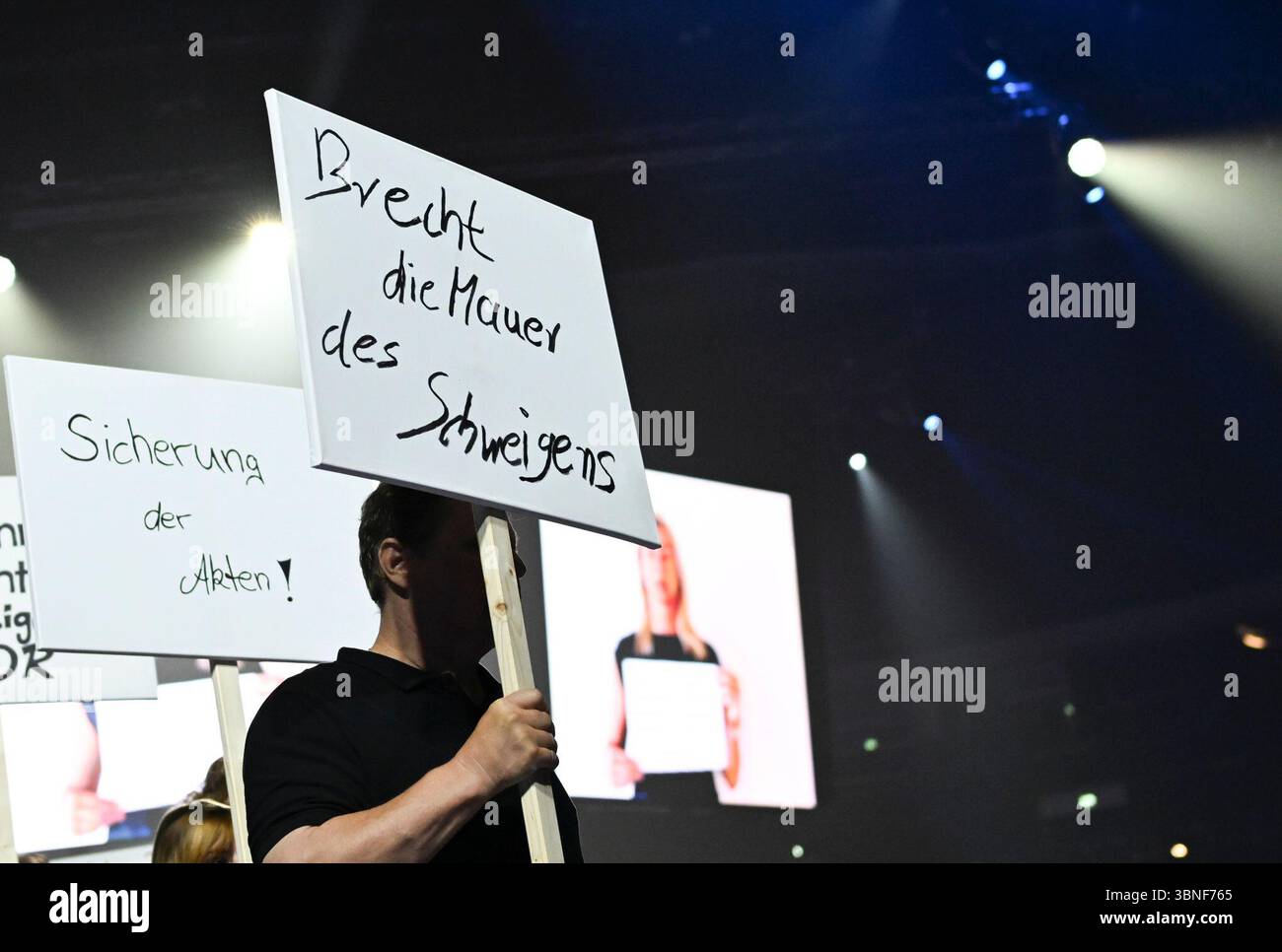 Berlin, Deutschland. Juli 2025. Als Teil der Show von Designer Kilian Kerner auf der Modeschau 'DDR. Die gestohlenen Kinder für Frühjahr/Sommer 2026 im Collevtivefour Space in der Uber Arena zeigen Models und Mitarbeiter Plakate zum Thema. Quelle: Jens Kalaene/dpa/Alamy Live News Stockfoto