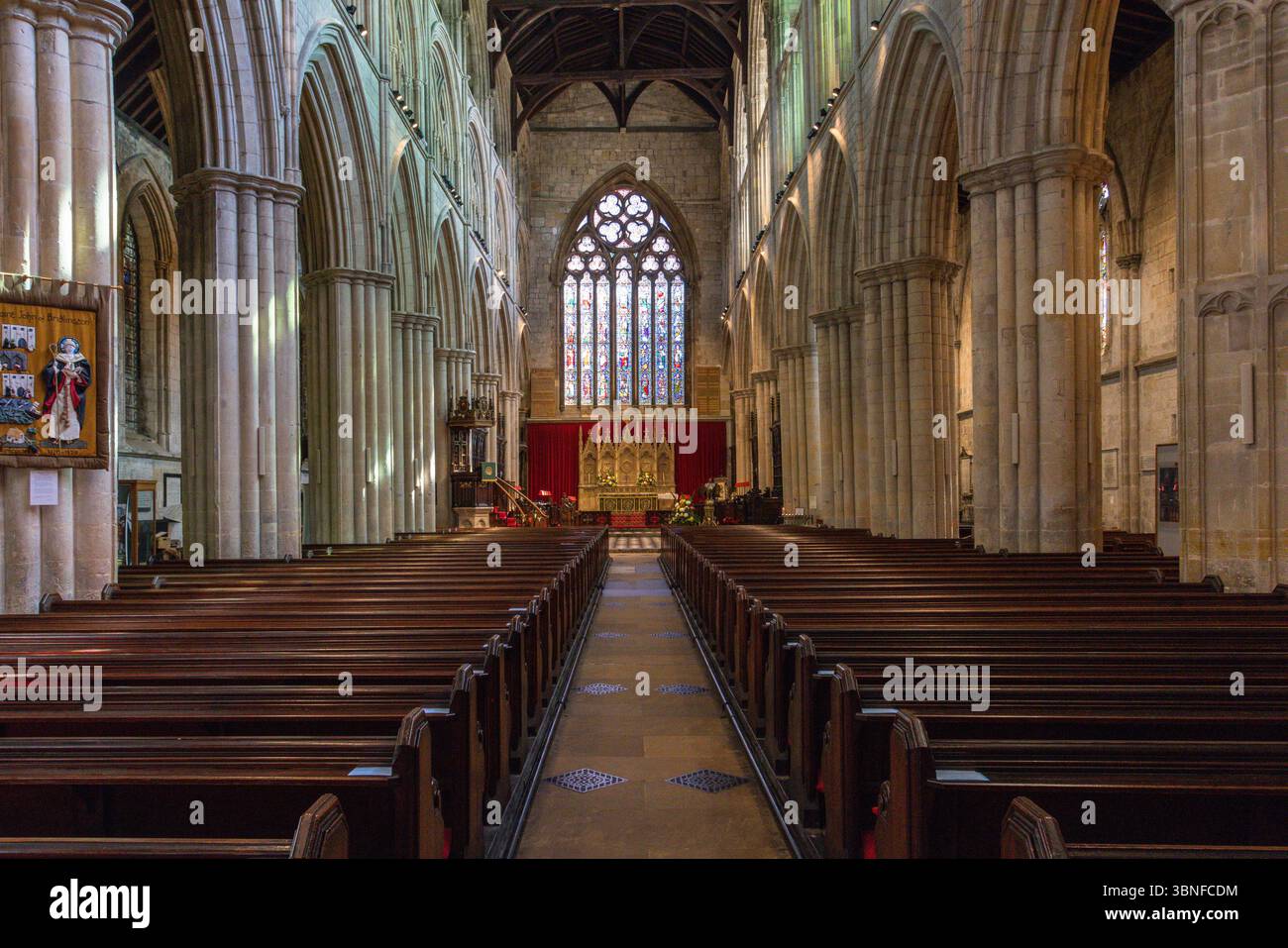 Das Schiff der Bridlington Priory erstreckt sich in Richtung des Buntglasfensters im Osten, mit großen Bögen und Steinsäulen, die das mittelalterliche Kircheninnere umrahmen. Stockfoto