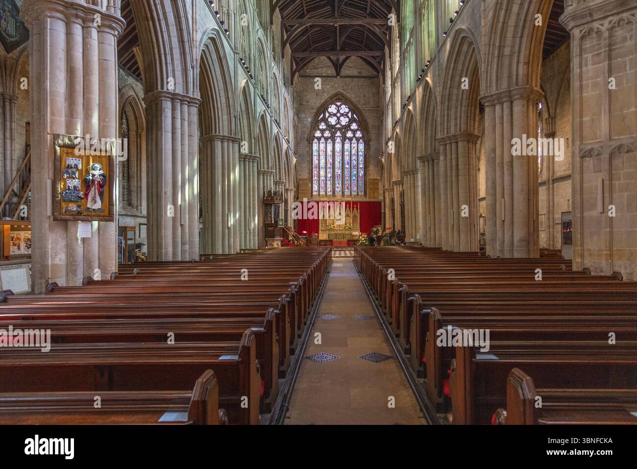 Das Schiff der Bridlington Priory erstreckt sich in Richtung des Buntglasfensters im Osten, mit großen Bögen und Steinsäulen, die das mittelalterliche Kircheninnere umrahmen. Stockfoto