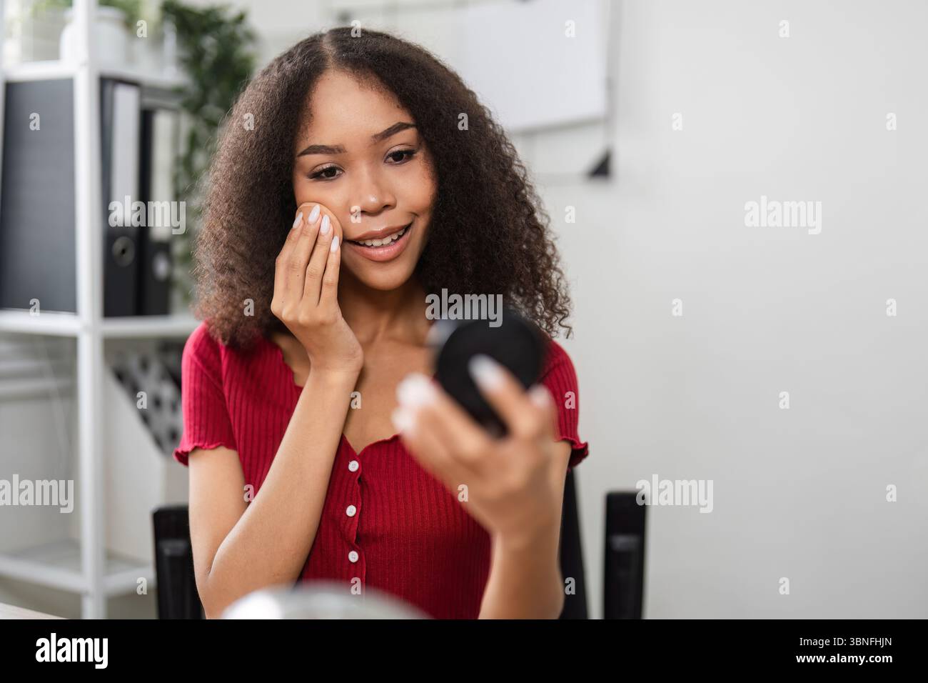 Natürliche Schönheit und Hautpositivität. Eine Frau, die ihren Make-up-Prozess mit einem fröhlichen Ausdruck genießt. Stockfoto
