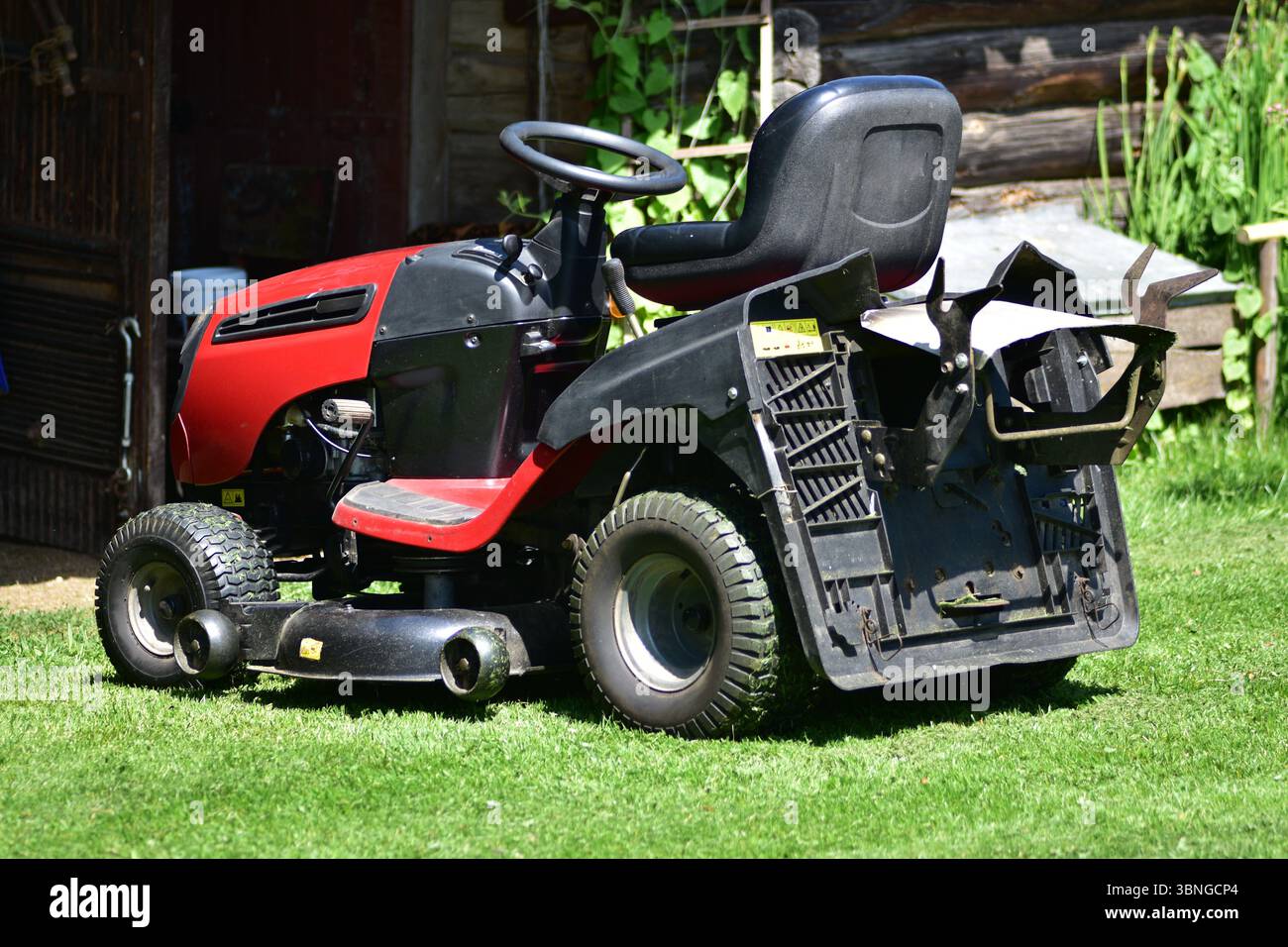 Rasenmäher in ländlicher Gegend in der Nähe des Eingangs der ländlichen Scheune. Gartenarbeit im Sommer, Konzept des ländlichen Lebensstils und Gartenmaintenan im Freien Stockfoto