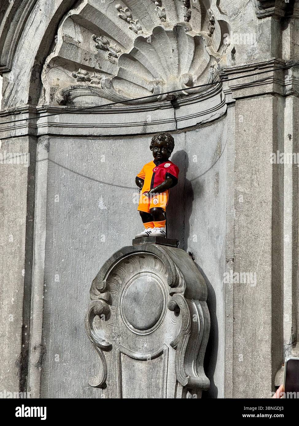 Die legendäre Statue Manneken Pis in Belgiens Trikot der belgischen Fußballnationalmannschaft in seiner Nische in Brüssel, Belgien. Stockfoto