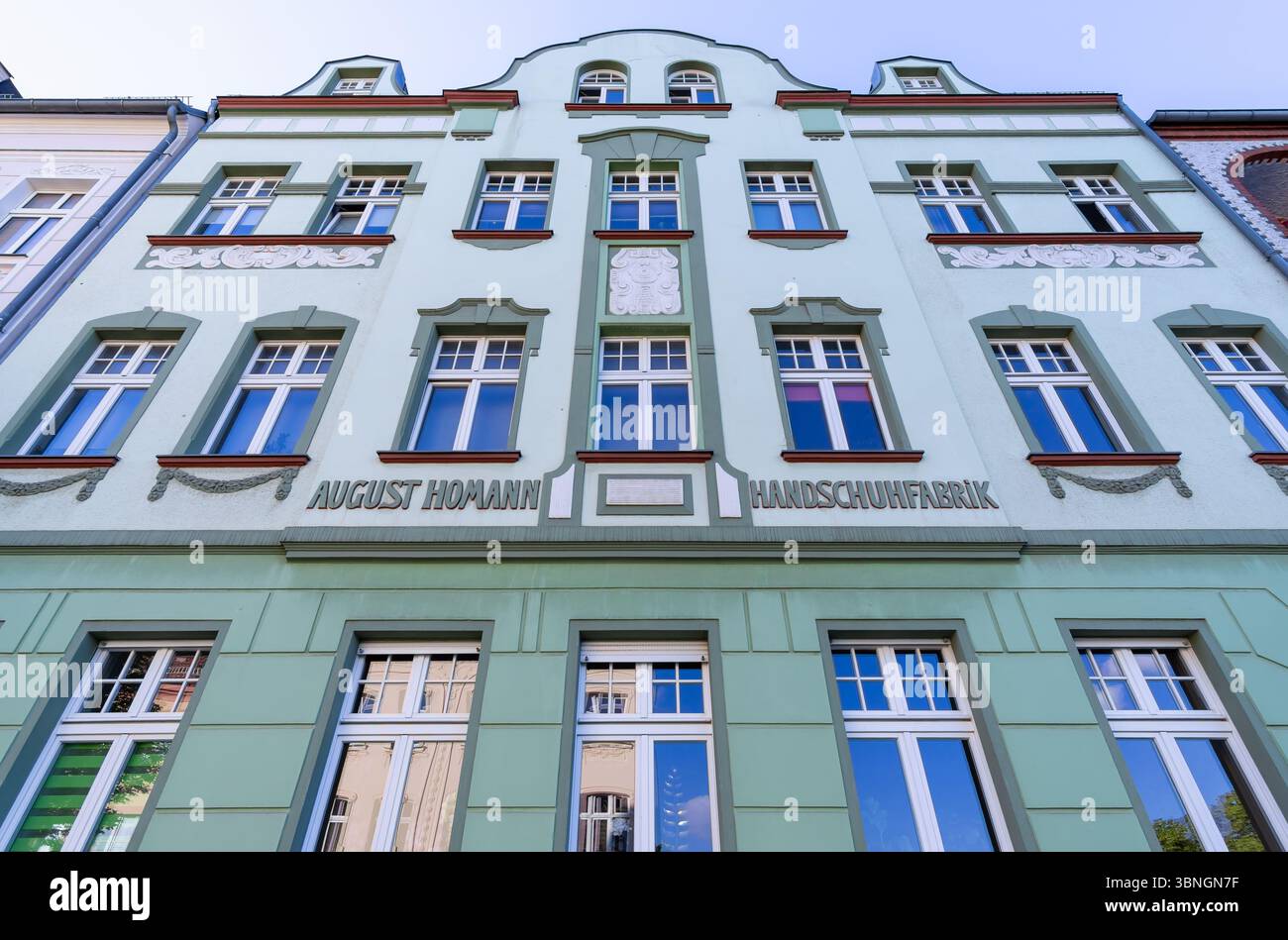 Historische Gebäudefassade der Handschuhfabrik August Homann in Bernau, Deutschland, mit architektonischen Details und Grüntönen. Stockfoto