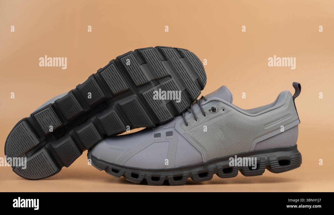 Graue Sportschuhe heben sich auf einem einfarbigen Hintergrund hervor und betonen stilvolles Design und Funktionalität für ein aktives Leben. Stockfoto
