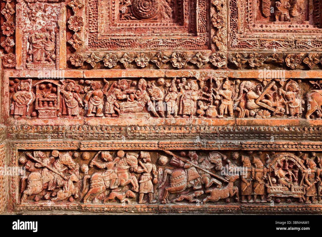 Detailliertes Terrakotta-Relief aus Puthias Pancha Ratna-Tempel mit hingebungsvollen Ritualen, göttlicher Geburt und reitenden Kriegern im Kampf. Stockfoto