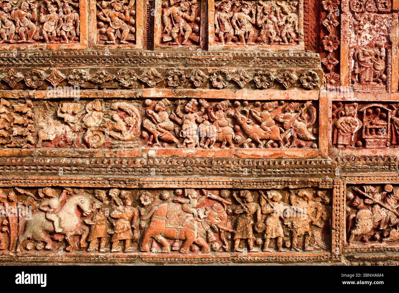 Terrakotta-Platte aus dem Pancha Ratna Govinda Tempel in Puthia, mit mythologischen Figuren, berittenen Kriegern und einer königlichen Elefantenprozession. Stockfoto